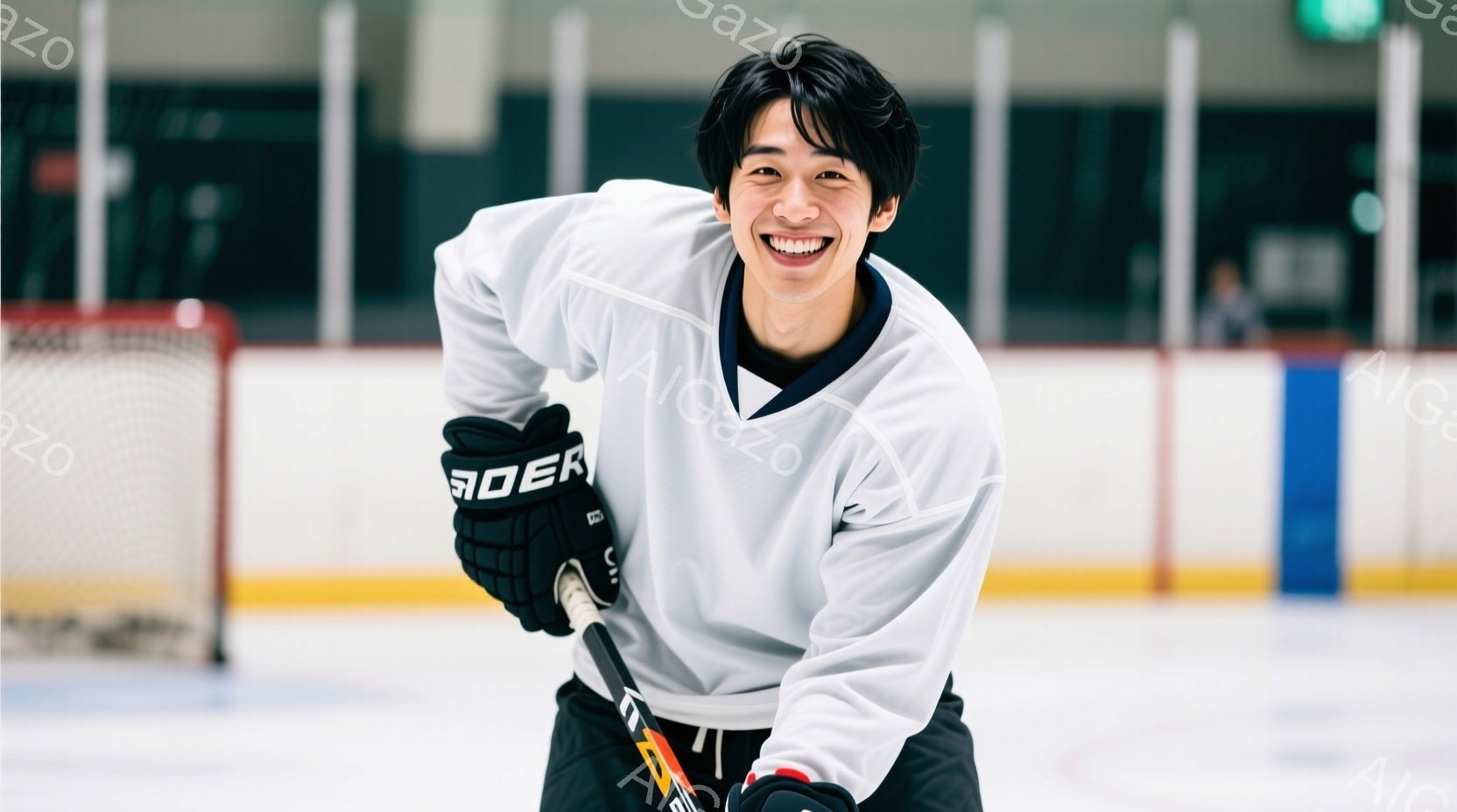リンクに立つ若い男性は、アイスホッケーのユニフォームと黒いグローブを身に着け、ホッケーのスティックを持っています。彼は満面の笑みを浮かべ、少し前かがみの姿勢で、活気に満ちた表情を見せています。背景にはアイスホッケーのゴールのネットと、ぼやけた観客席が見え、競技場の明るい照明が全体を照らしています。