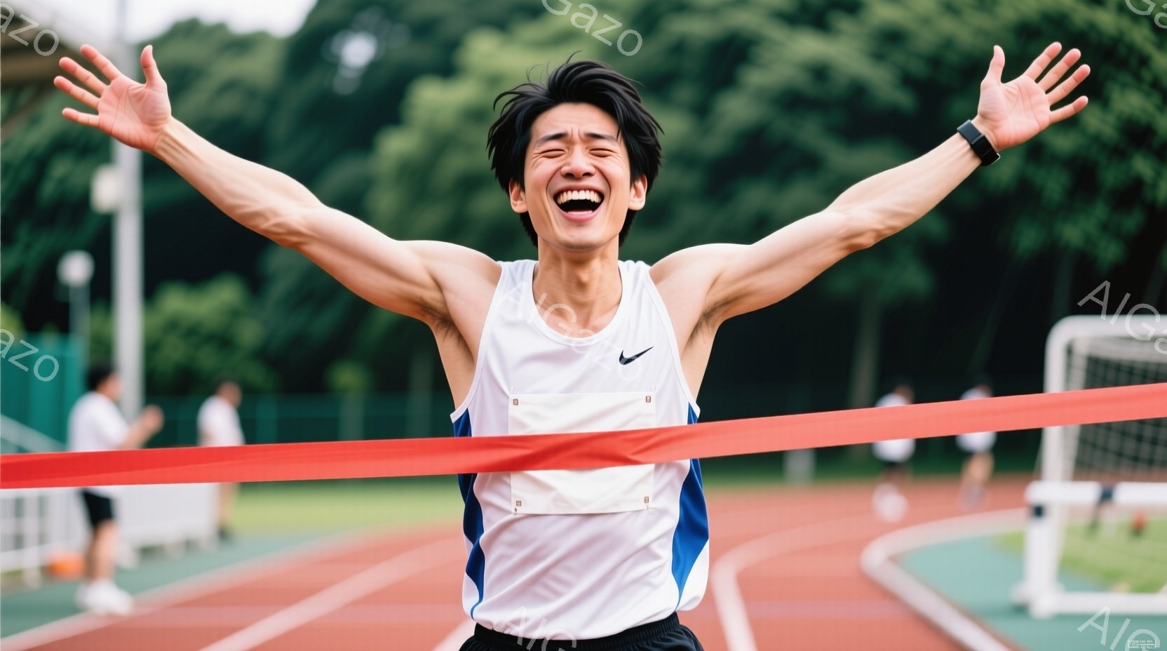 白いタンクトップと黒の短パンを着た若い男性が、赤いフィニッシュラインを駆け抜けている。彼は両腕を高く上げ、満面の笑みを浮かべており、勝利の喜びを表現している。背景には緑の芝生、トラック、そして白いフェンスが見え、晴れた日の競技場の活気ある雰囲気が伝わってくる。