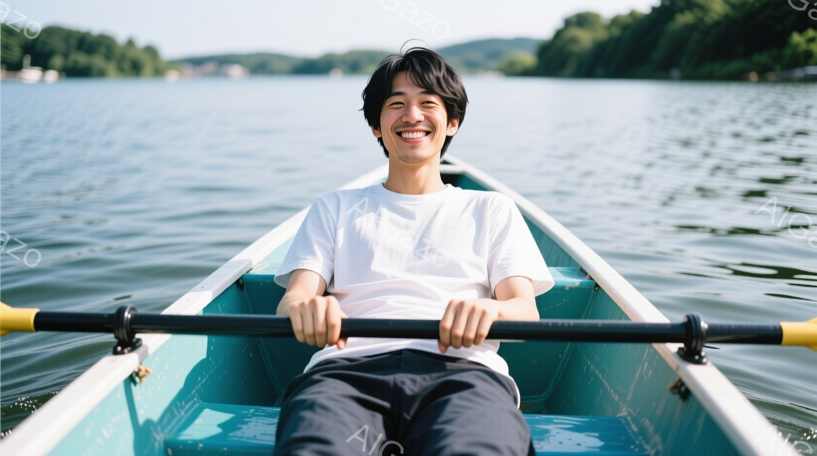 若い男性がボートに乗って漕いでいる様子が写っている。彼は白いTシャツと黒いパンツを着用し、少し笑顔を浮かべている。背景には緑豊かな山々と穏やかな水面が広がり、晴れた日の穏やかな雰囲気が伝わってくる。