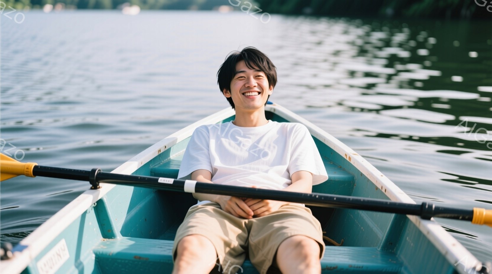 若い男性が水色のボートに座り、満面の笑みを浮かべている。彼は白いTシャツとベージュのショートパンツを着用し、短く黒い髪をしている。背景は穏やかな湖で、緑豊かな木々が見え、晴天で波紋が光っている。 - AI生成フリー素材