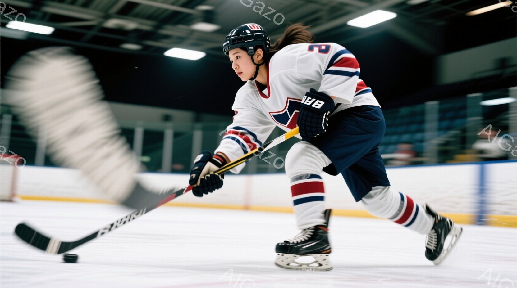 アイスホッケー選手がリンク上でパックを打ち、激しいプレーを見せています。彼は白、赤、青のチームジャージとヘルメットを身につけ、黒いヘアスタイルで集中した表情でプレーに臨んでいます。背景には観客席が見え、リンク全体が明るく照らされ、ダイナミックな雰囲気を醸し出しています。