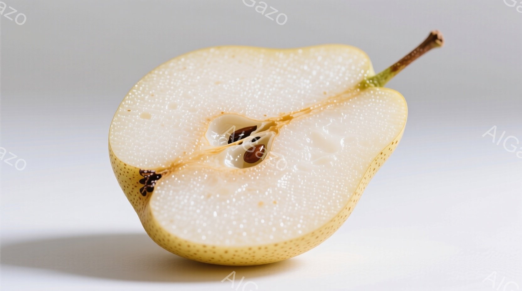 梨の半分が、白っぽい背景の上に置かれています。果肉は淡いクリーム色で、中央には小さな茶色の種が並んでいます。光が柔らかく当たり、梨の表面に微妙な影を作り出しています。 - AI生成フリー素材