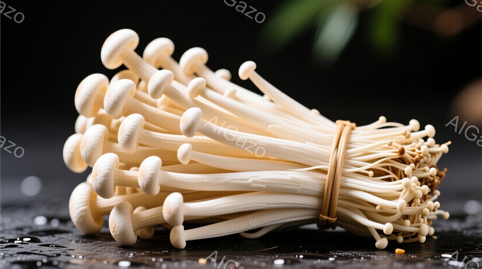 束ねられたエリンギが黒い表面に置かれています。キノコは白く細長く、先端がわずかに膨らんでおり、全体的に新鮮で清潔な印象を与えます。背景は暗く、水滴が見て取れ、キノコを際立たせています。