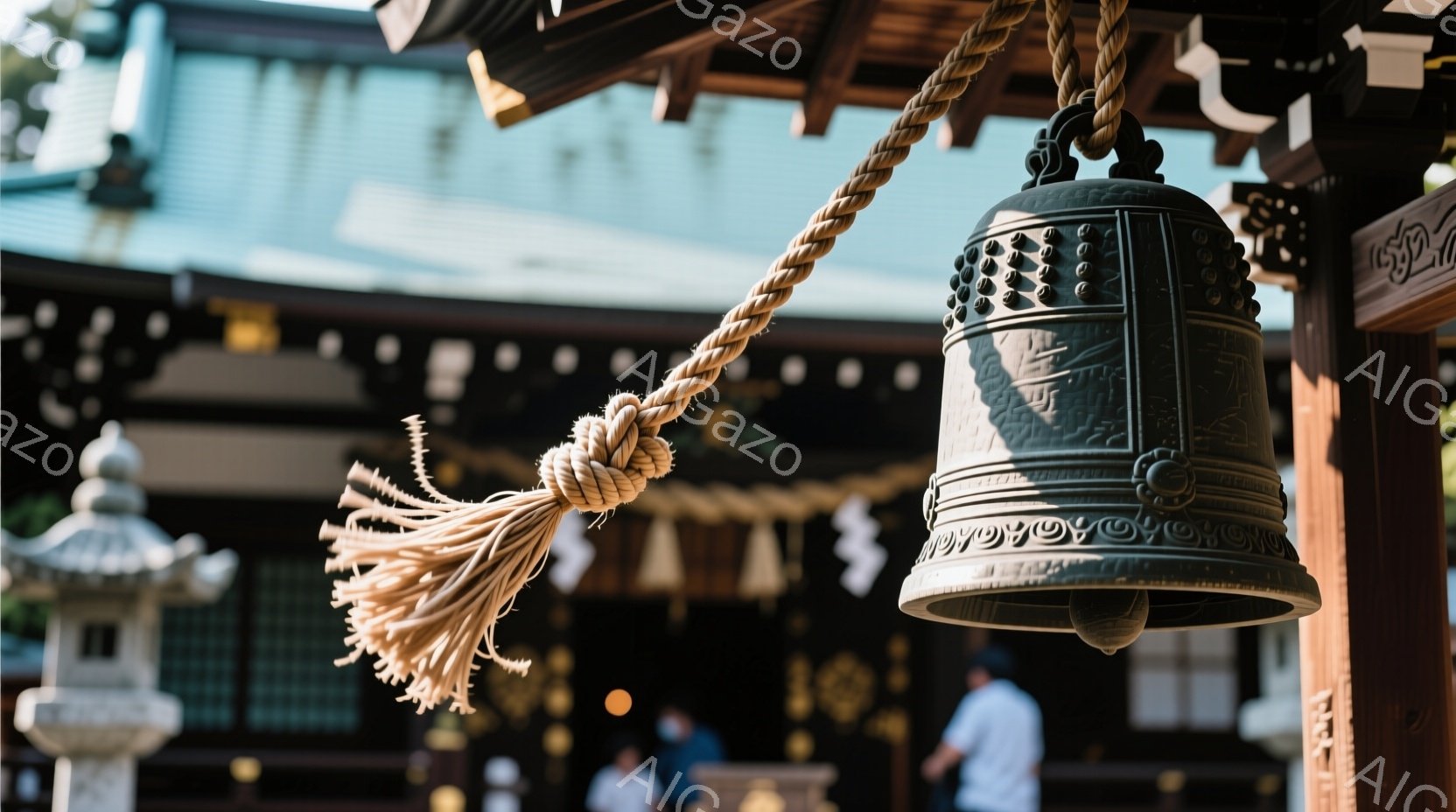 古い寺院の鐘が画像の中央に位置し、粗い麻紐で吊り下げられています。鐘の表面には複雑な模様が刻まれ、歴史と風格を感じさせます。背景には木造建築の一部が見え、ぼんやりと人影があり、静かで神聖な雰囲気が漂っています。