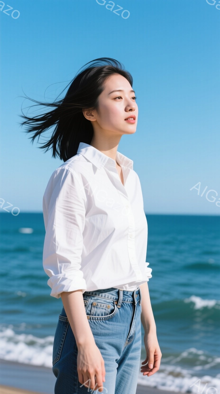 海岸を背景に、白いシャツとデニムを着た若い女性が立っている。彼女は少し横を向き、風になびく黒髪が印象的で、穏やかな表情で遠くを見つめている。青い空とエメラルドグリーンの海が広がり、爽やかで開放的な雰囲 - AI生成フリー素材
