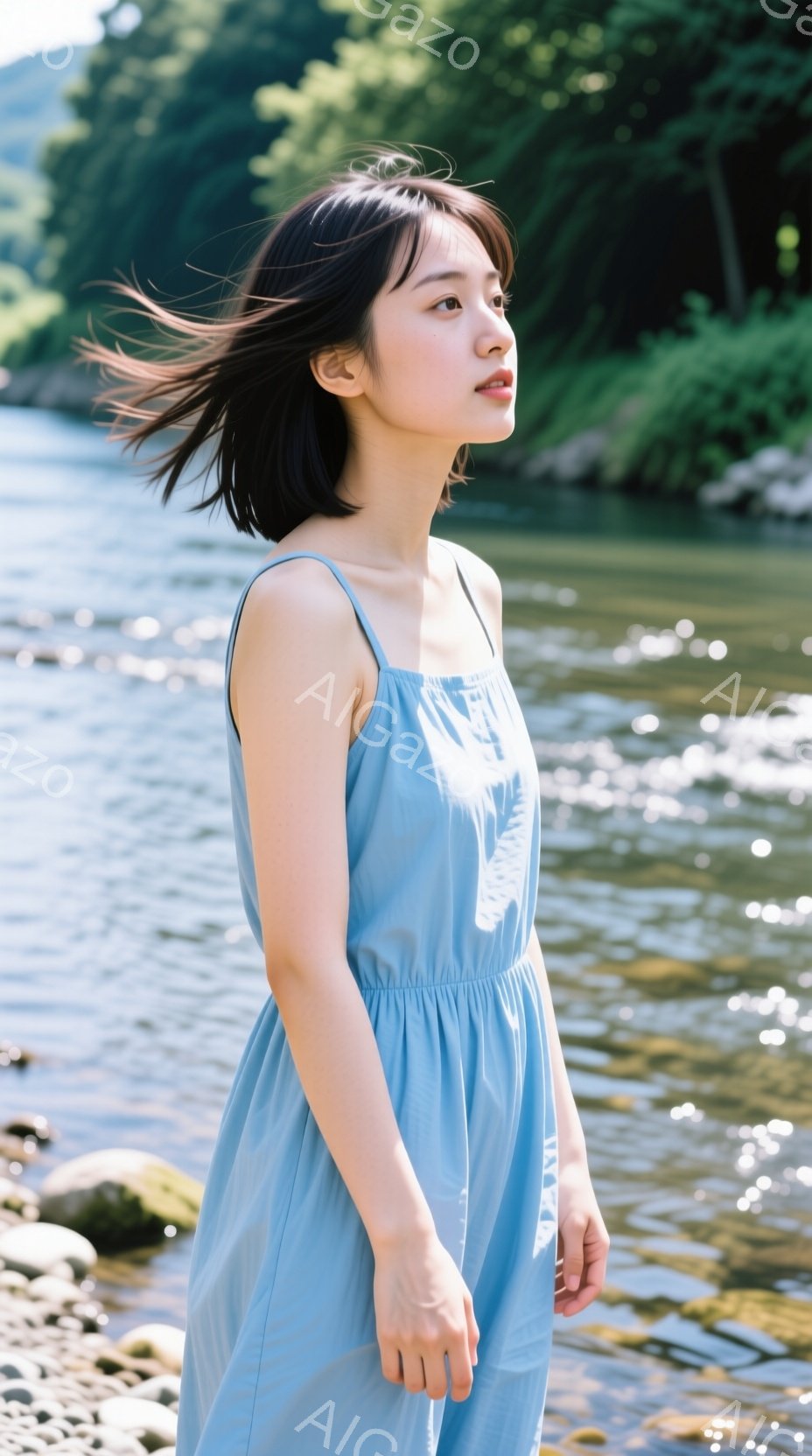水色のキャミソールワンピースを着た若い女性が、川沿いの石の上で立っている。彼女は少し顔を上げ、遠くを見つめており、髪は風になびいている。背景には緑豊かな木々と、光が反射する川の流れがあり、穏やかで自然 - AI生成フリー素材