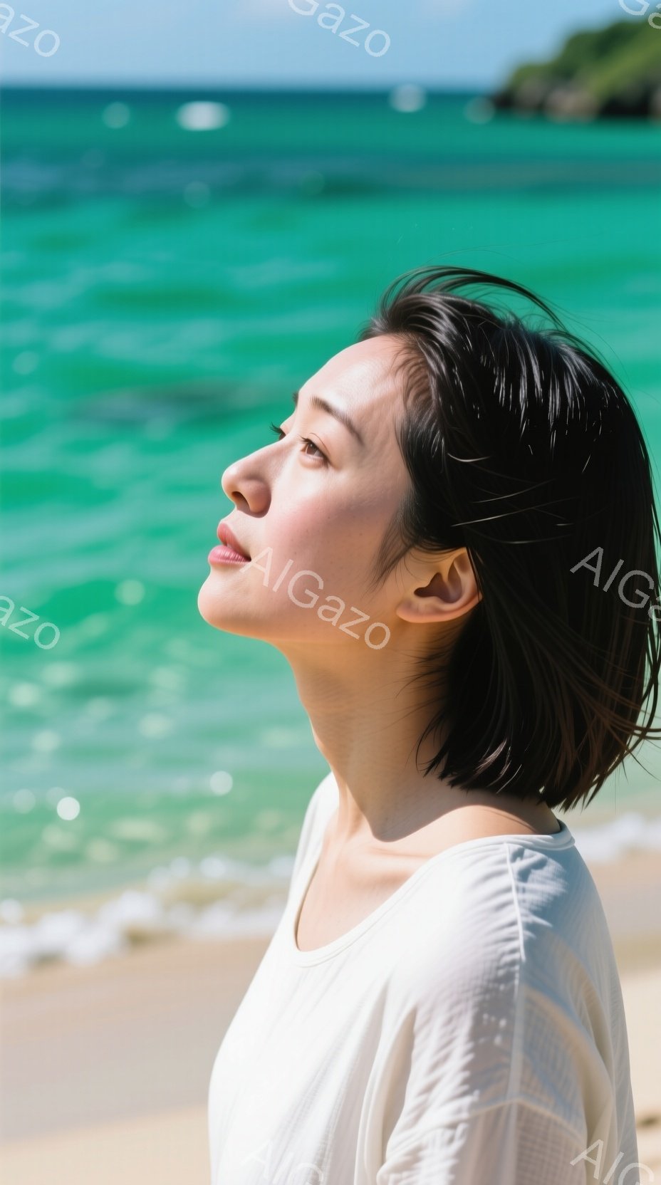 短い黒髪の女性が、白いブラウスを着て砂浜に立っている。彼女は目を閉じて顔を上げ、太陽の光を浴びているようで、リラックスした穏やかな表情をしている。背景にはターコイズブルーの海と白い波が広がり、晴天で穏やかな夏の日の雰囲気が漂っている。