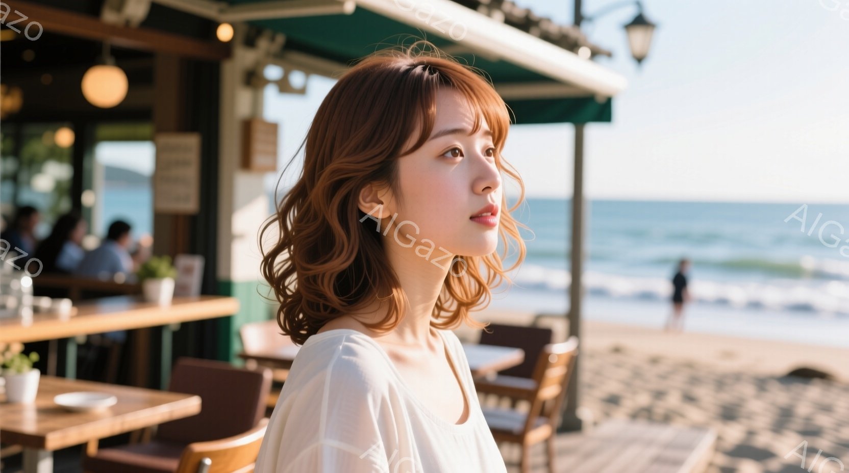 明るい茶髪の女性が、白いブラウスを着て少し横を向いています。彼女はリラックスした表情で、穏やかな海を眺めているようです。背景にはカフェのテラス席と、青い海、そして白い砂浜が広がり、晴れた日の穏やかな雰囲気を醸し出しています。