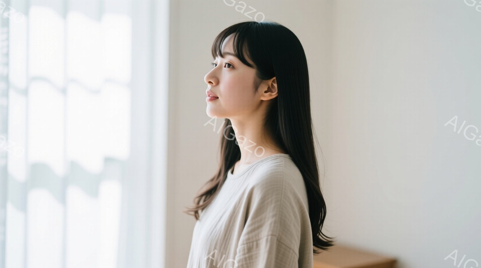 長い黒髪の女性が、窓辺で横顔を見せています。ベージュ色のシンプルなトップスを着ており、穏やかな表情でどこかを見つめています。背景はぼやけた白い壁と窓で、柔らかく静謐な雰囲気が漂っています。 - AI生成フリー素材