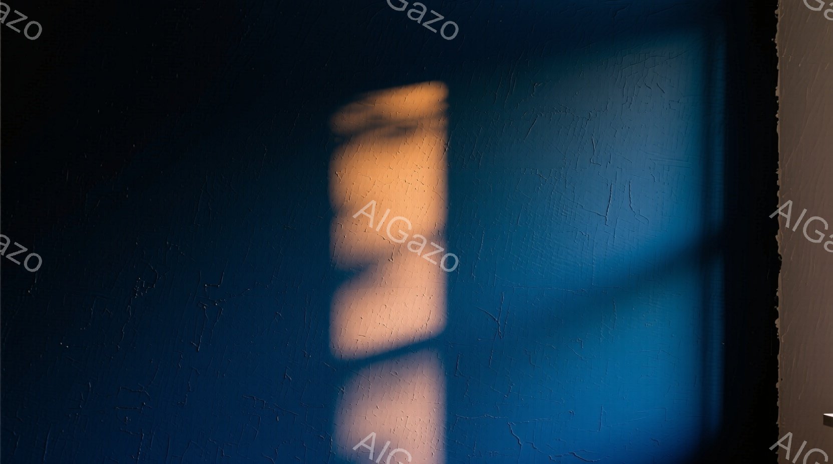 鮮やかなコバルトブルーの壁に、人物の影が映っています。影は上半身のみで、おそらく女性のシルエットと思われ、髪は肩にかかるくらいの長さで、何かを見つめているような姿勢です。影のコントラストが強く、壁のテクスチャが強調され、ミステリアスで静謐な雰囲気を醸し出しています。