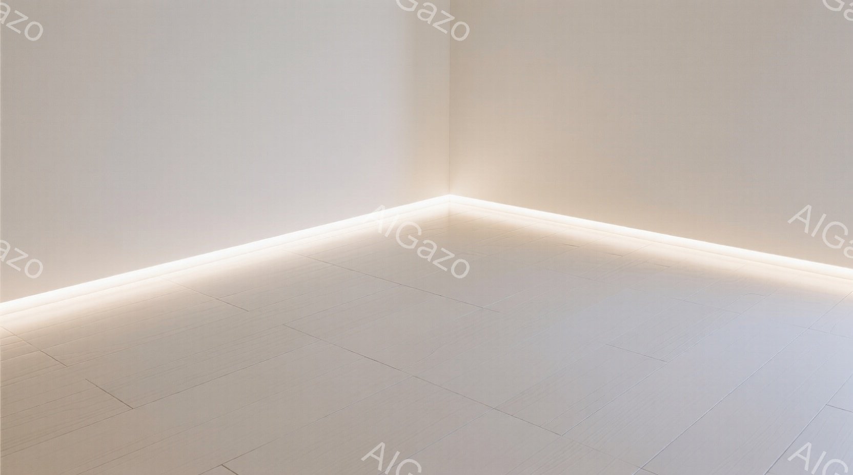 白い壁と床が続く、ミニマルな空間が写っている。床面には白いタイルが敷き詰められ、壁の裾を明るい光が縁取っているため、部屋の隅が強調されている。全体的に清潔感があり、静かで穏やかな雰囲気が漂っている。
