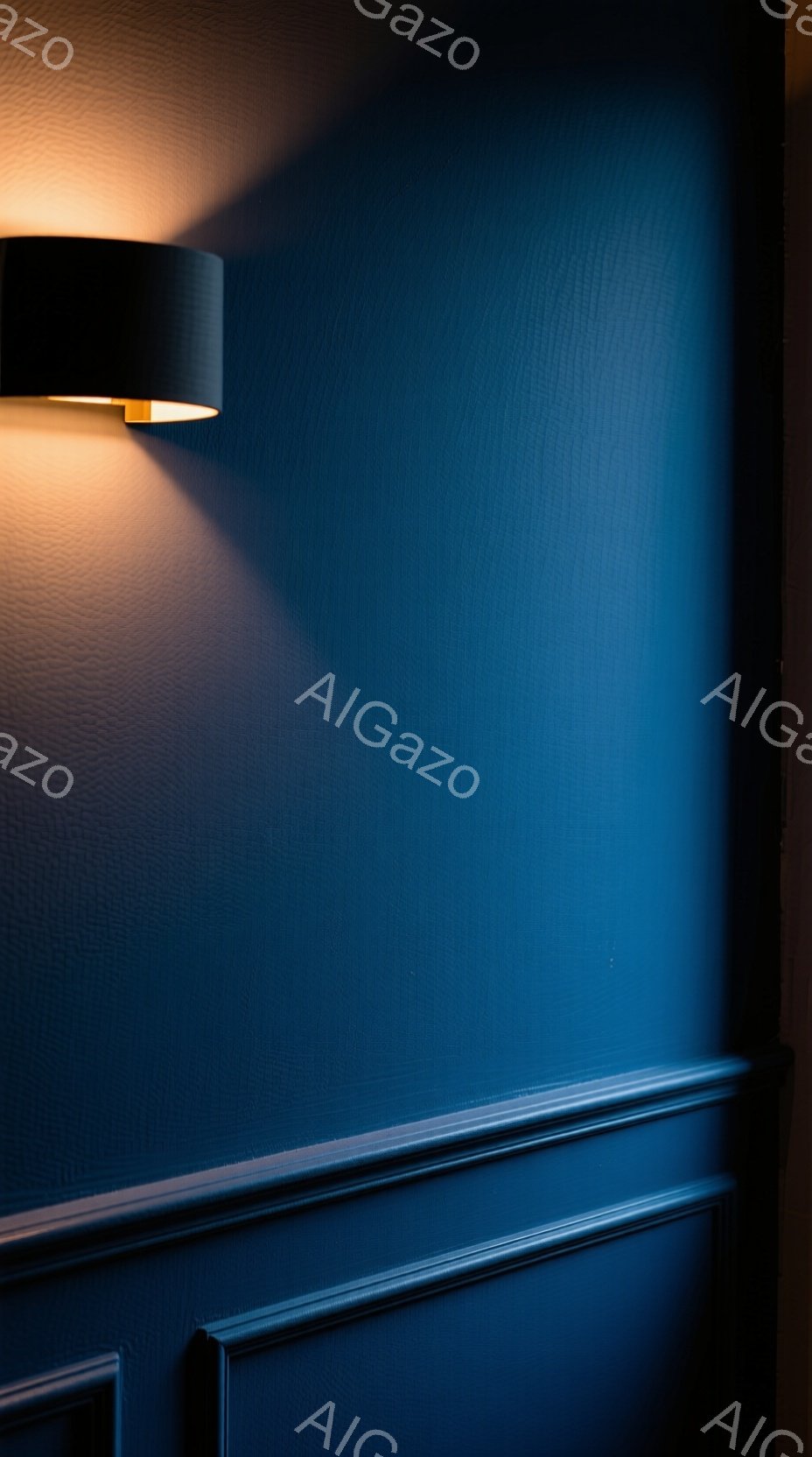 深い藍色の壁が印象的な画像です。壁には装飾的なモールディングが施されており、上部から光が当たることで、立体感が強調されています。光の色合いは暖かく、壁の冷たい色調とのコントラストが、落ち着いた雰囲気を醸し出しています。