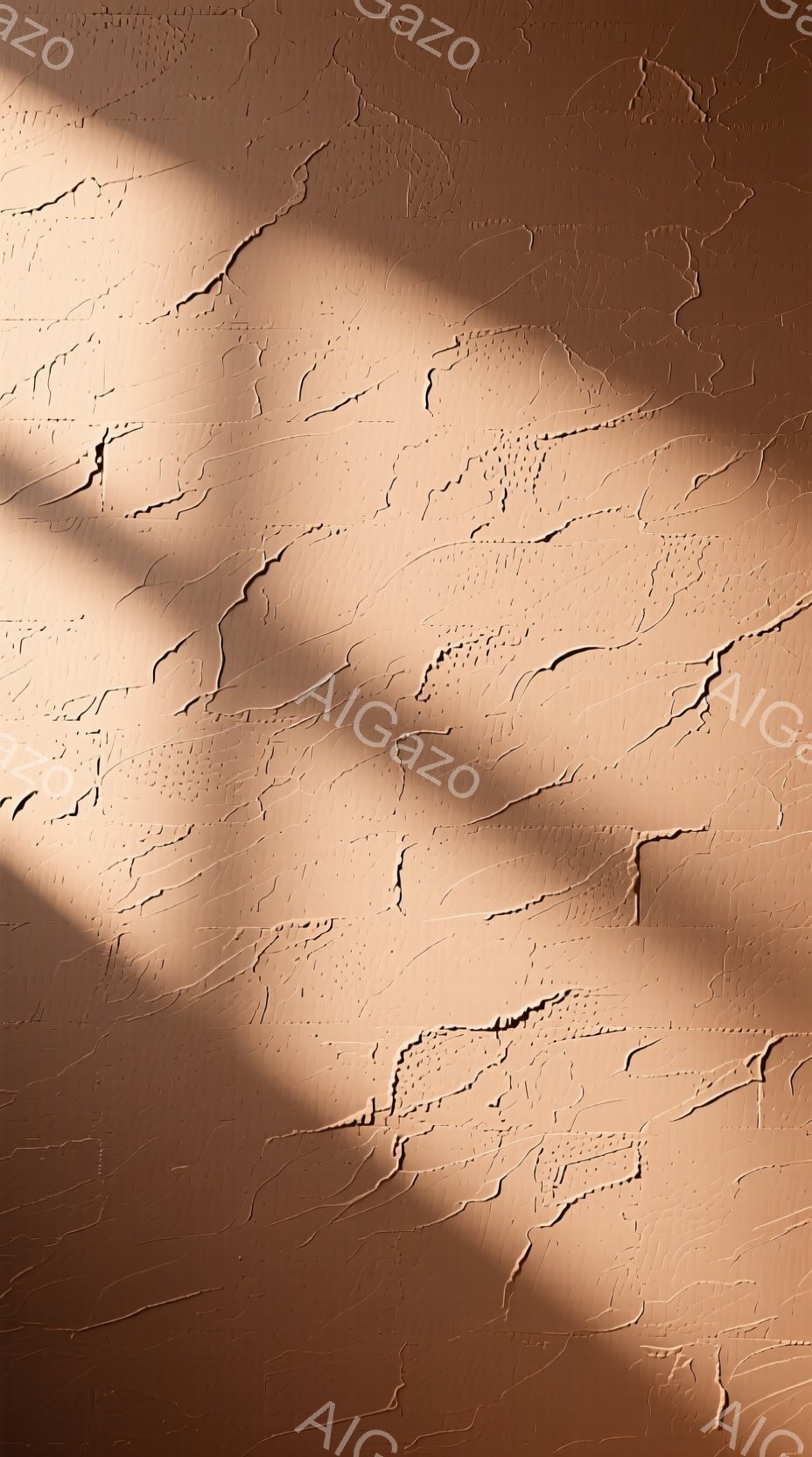 ざらざらとした質感のベージュ色の壁面が画面全体を占めている。壁には、まるでひび割れのような、または土地の隆起のような模様が複雑に入り組んでおり、独特の陰影を生み出している。左上には、葉っぱまたは植物の影が落ちており、静かで落ち着いた雰囲気を醸し出している。