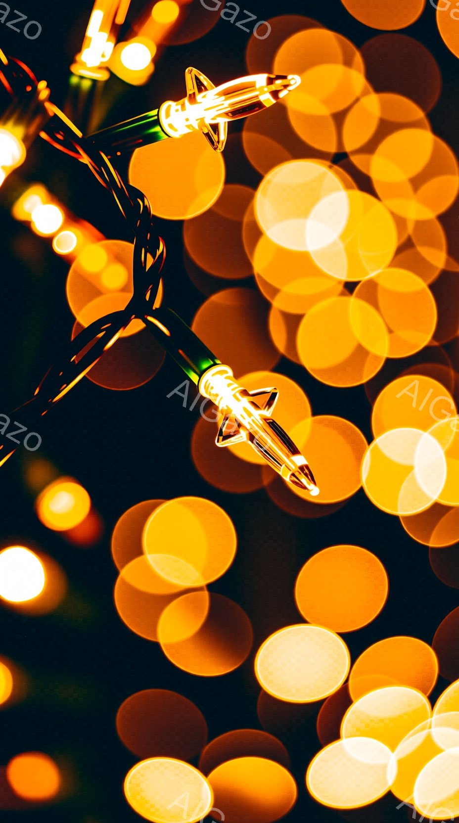 暖色系のぼやけた光が背景に広がり、クリスマスのイルミネーションの電球が焦点となっています。緑色のコードに接続された小さな電球は、ぼやけた光の中で輝き、冬の祝祭の雰囲気を作り出しています。全体として、暖かく、お祝いの、そして少し幻想的な雰囲気です。