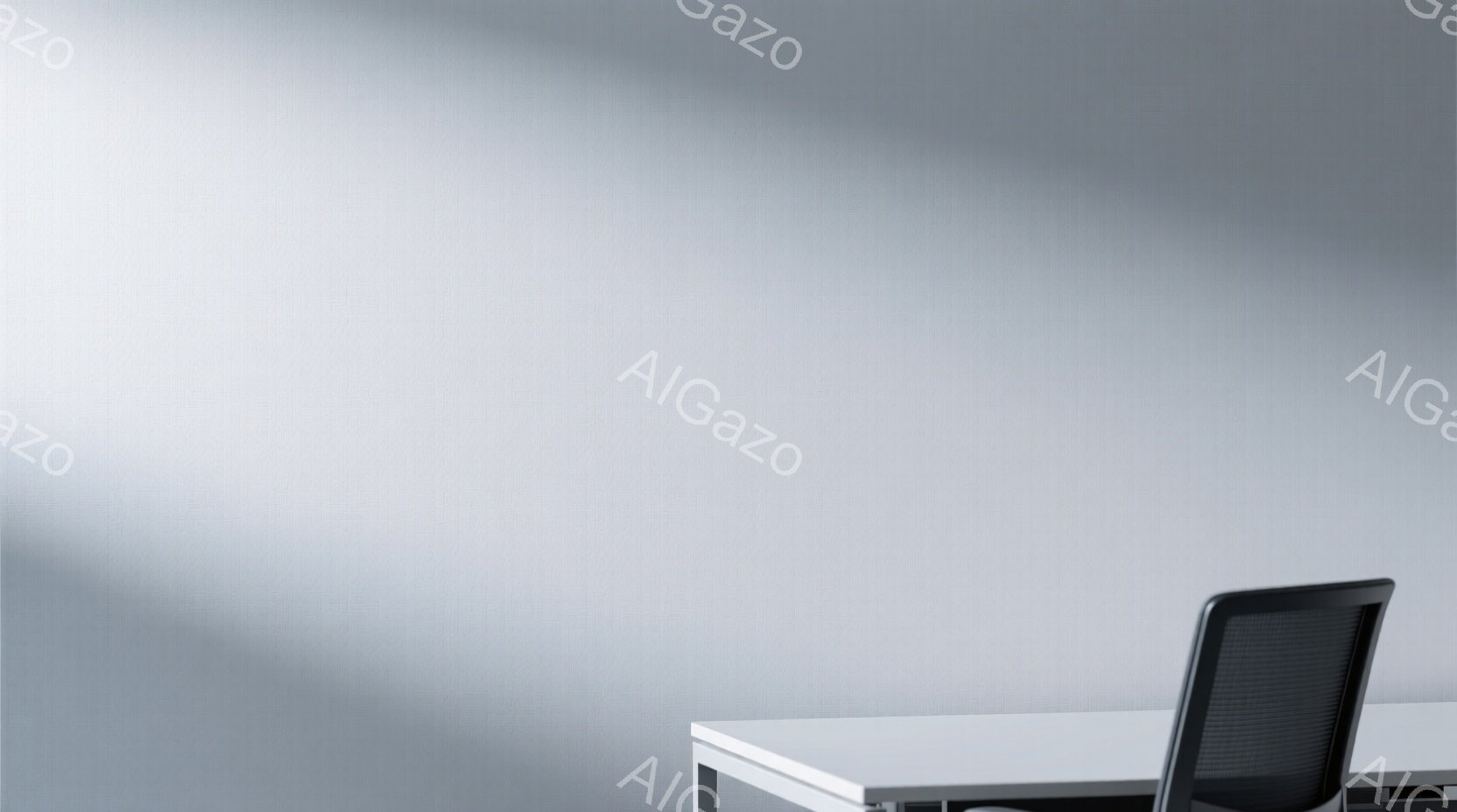 白い壁を背景に、黒い事務用椅子と白いデスクが配置されているシンプルな室内風景です。デスクはきれいに整頓されており、現代的でミニマリストな雰囲気を醸し出しています。光の当たり具合から、静かで落ち着いた空間であることが伺えます。