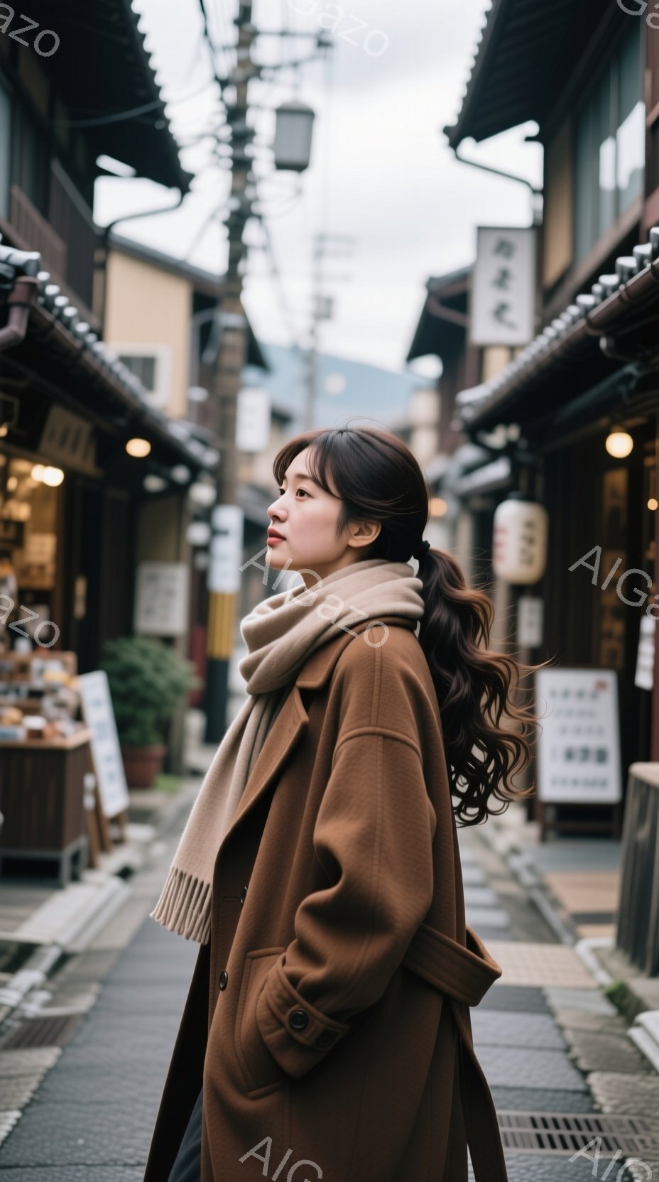 茶色のオーバーコートとスカーフを身に着けた女性が、古い街並みを歩いている。彼女は髪をハーフアップにしており、横顔は穏やかでどこか物憂げだ。背景には木造の建物が並び、石畳の道と曇り空が、懐かしい雰囲気を醸し出している。