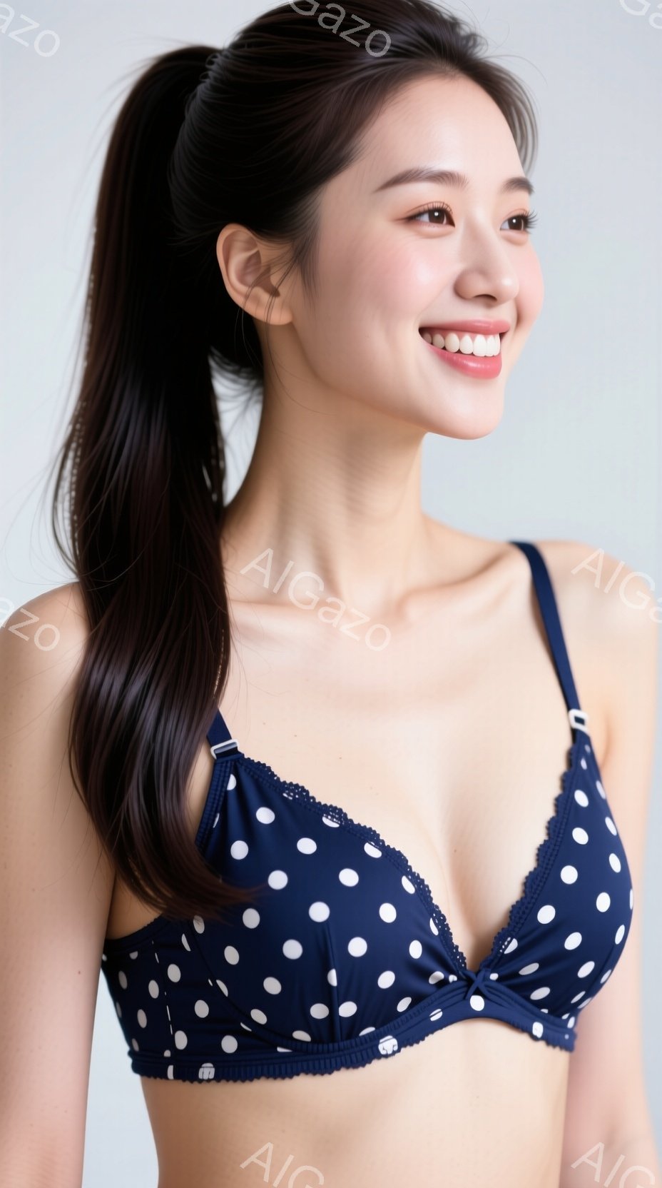 長い黒髪をポニーテールにした女性が写っています。彼女は濃紺地に白い水玉模様のブラレットを着用し、顔には穏やかな笑顔が浮かんでいます。背景は白く、人物が際立っており、全体的に清潔感のある、明るい雰囲気が - AI生成フリー素材