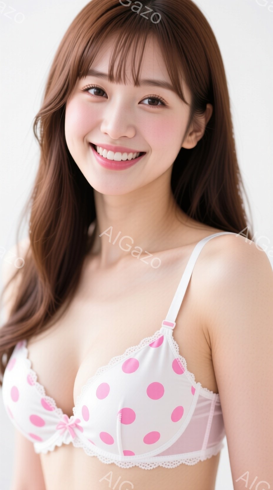 長い茶色の髪に前髪が特徴的な女性が、白地にピンクの水玉模様のブラジャーを着用して正面を向いています。彼女は微笑んでおり、リラックスした姿勢でカメラを見ています。背景は白でシンプルであり、女性が主役となっている構図です。