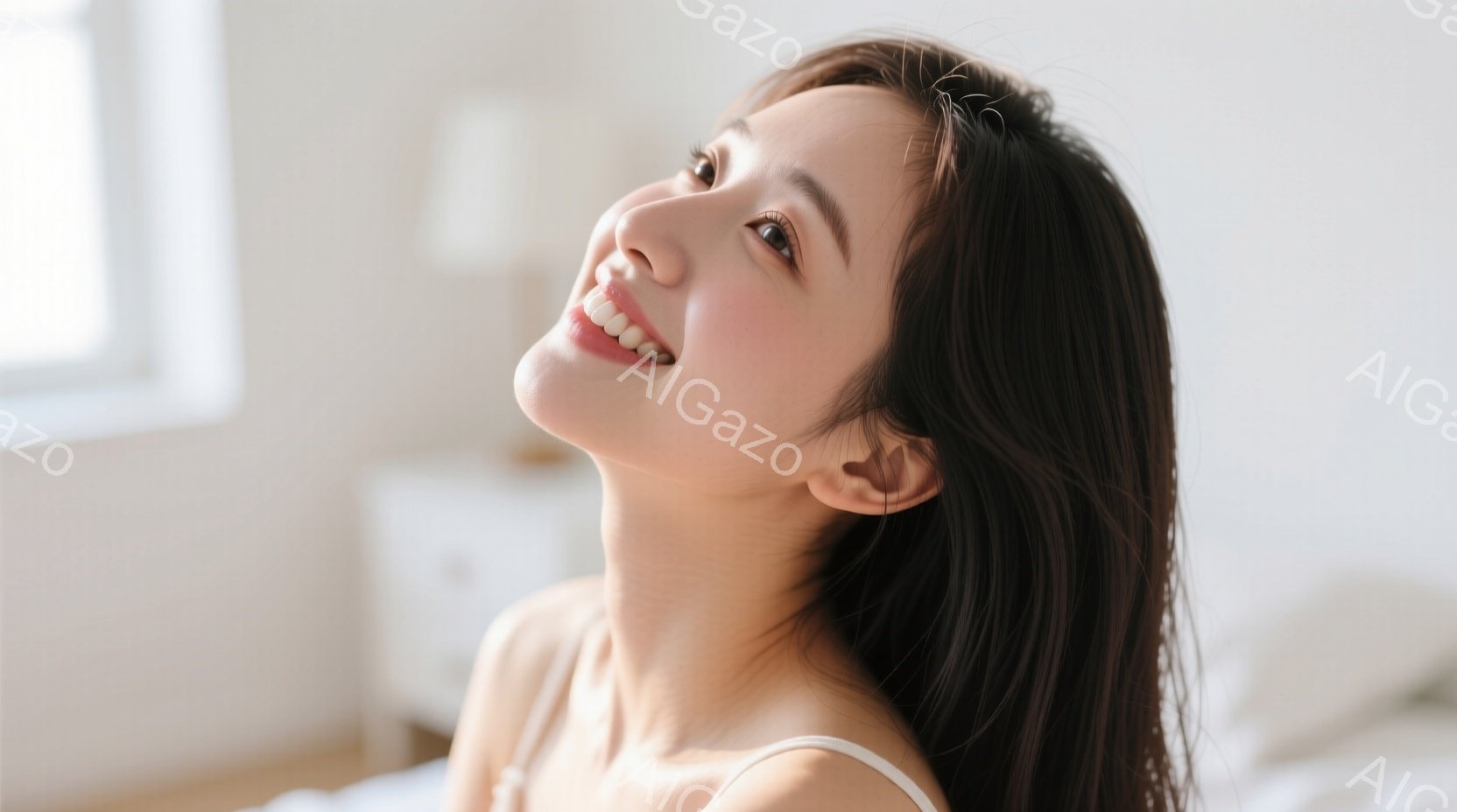長い黒髪の女性が、わずかに上を見上げて微笑んでいる。白いストラップのトップスを着ており、柔らかな光の中で肌が明るく輝いている。背景はぼやけているが、白い家具が見え、部屋全体が清潔で穏やかな雰囲気を醸し出している。