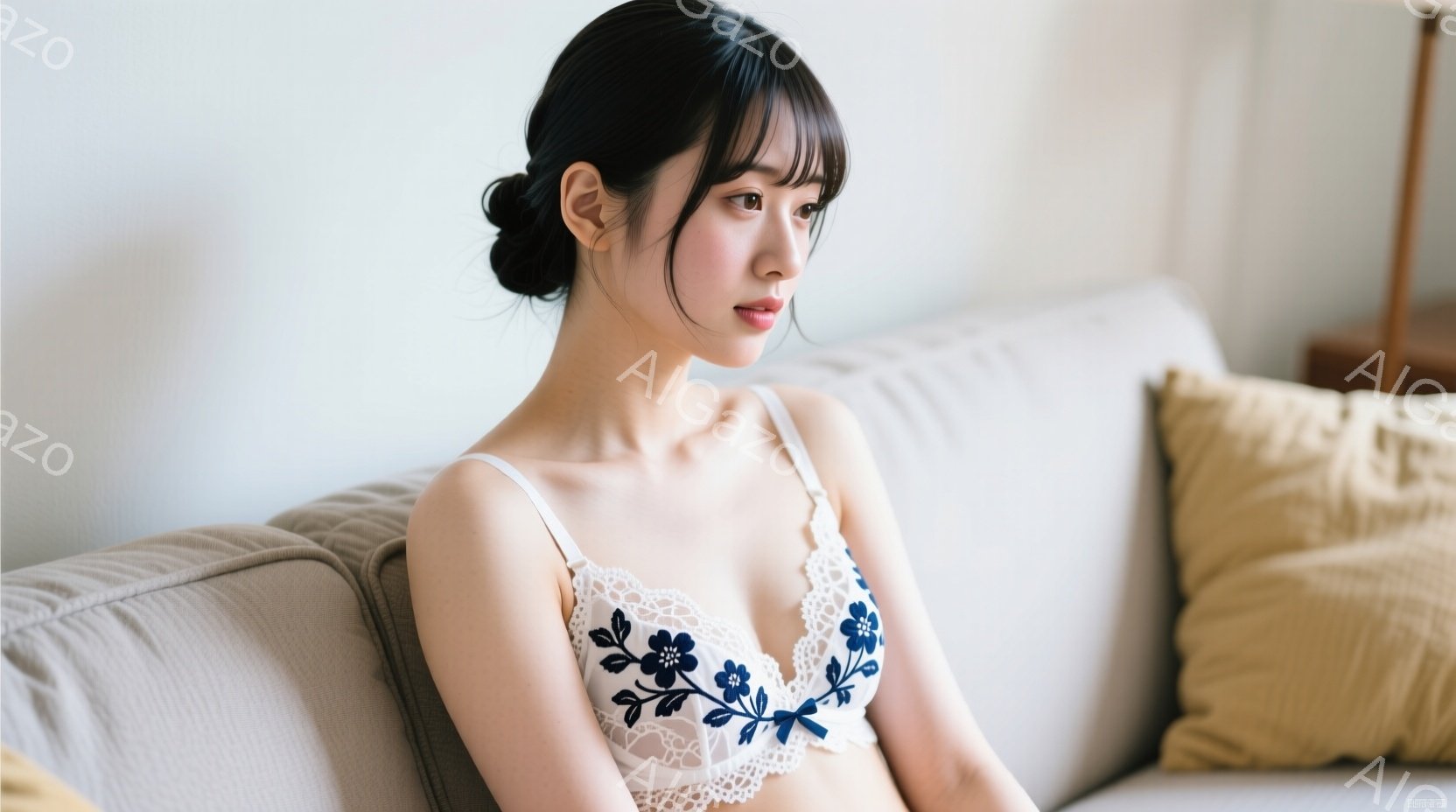 明るい色のソファに座る若い女性が写っています。彼女は白いレースと紺色の花柄のブラレットを着ており、黒髪を後ろで緩くまとめ、少し物憂げな表情を浮かべています。背景にはぼんやりと家具が見え、全体的に柔らか - AI生成フリー素材