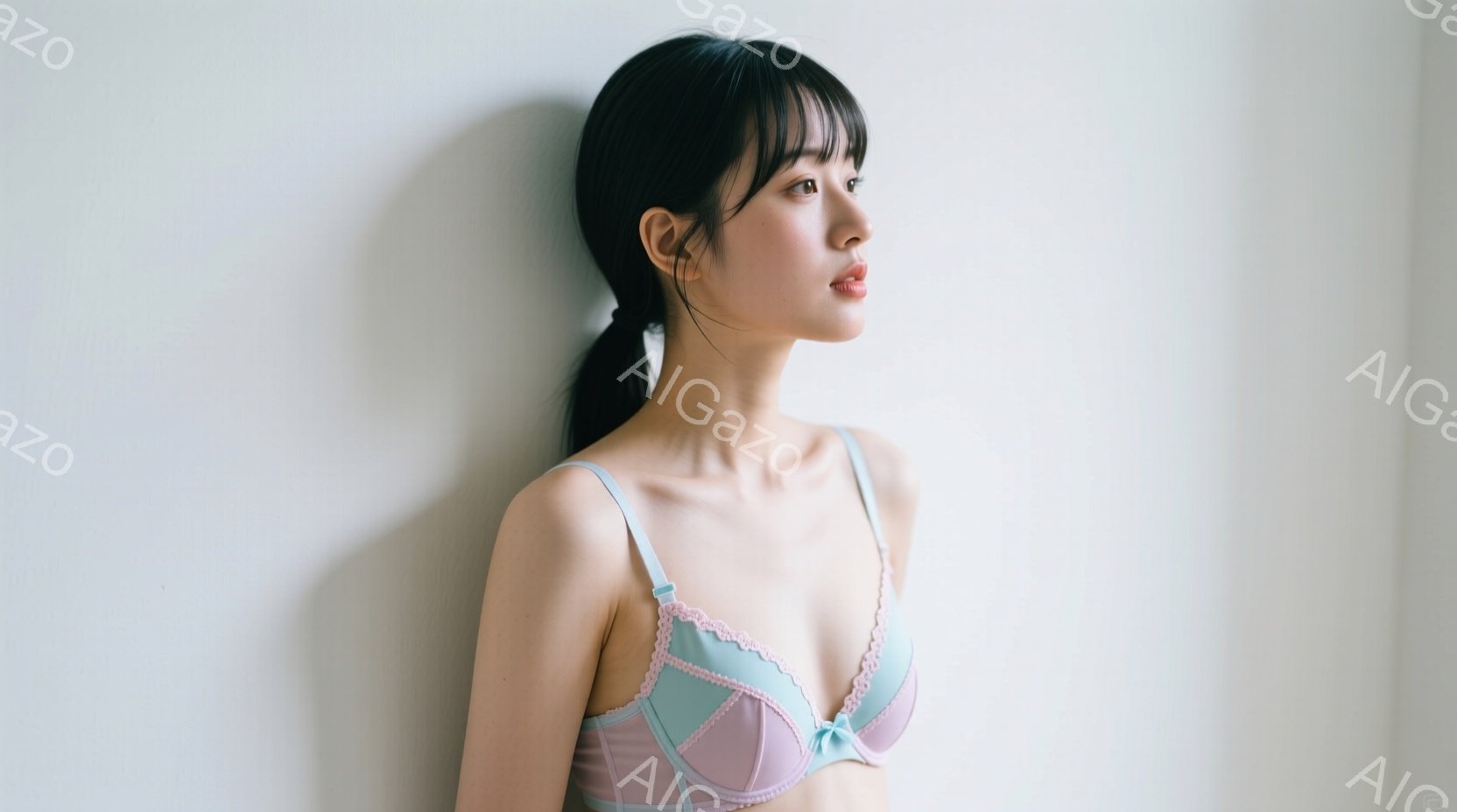 若い女性が淡いピンクと水色のレースのブラレットを着用し、横顔を見せています。彼女は黒髪で前髪を伸ばし、ポニーテールにまとめています。背景は白壁で、全体的に柔らかく、静謐な雰囲気を醸し出しています。