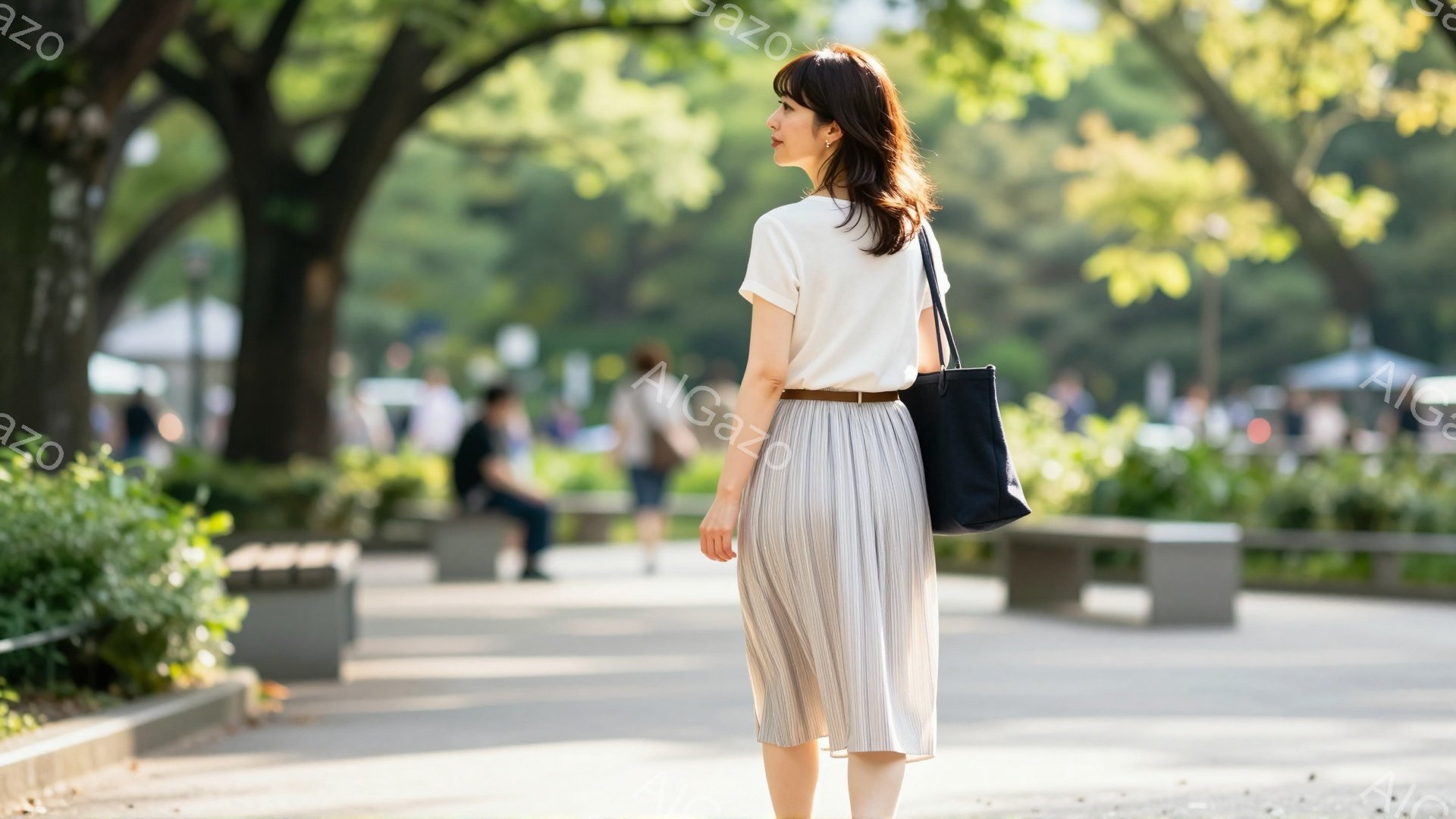 白いTシャツに薄いベージュのプリーツスカートを着用した女性が、公園の道を歩いている後ろ姿が捉えられている。彼女は黒いショルダーバッグを肩にかけ、カジュアルながらも上品な印象を与える服装をしている。背景 - AI生成フリー素材