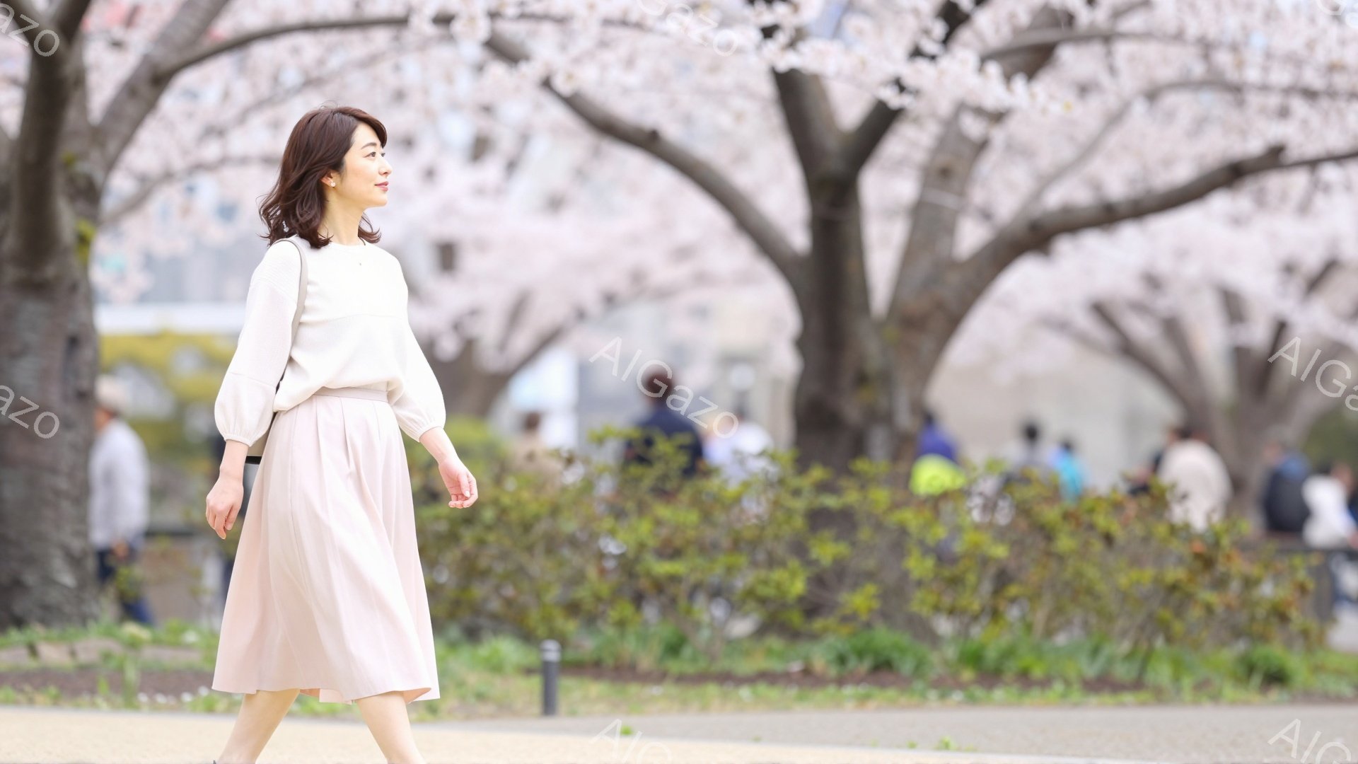 画像には、ピンク色のスカートと薄いベージュ色のブラウスを着た女性が写っています。彼女は歩きながら、やや微笑んでいます。背景には桜並木が咲き誇り、春の暖かく穏やかな雰囲気が漂っています。 - AI生成フリー素材