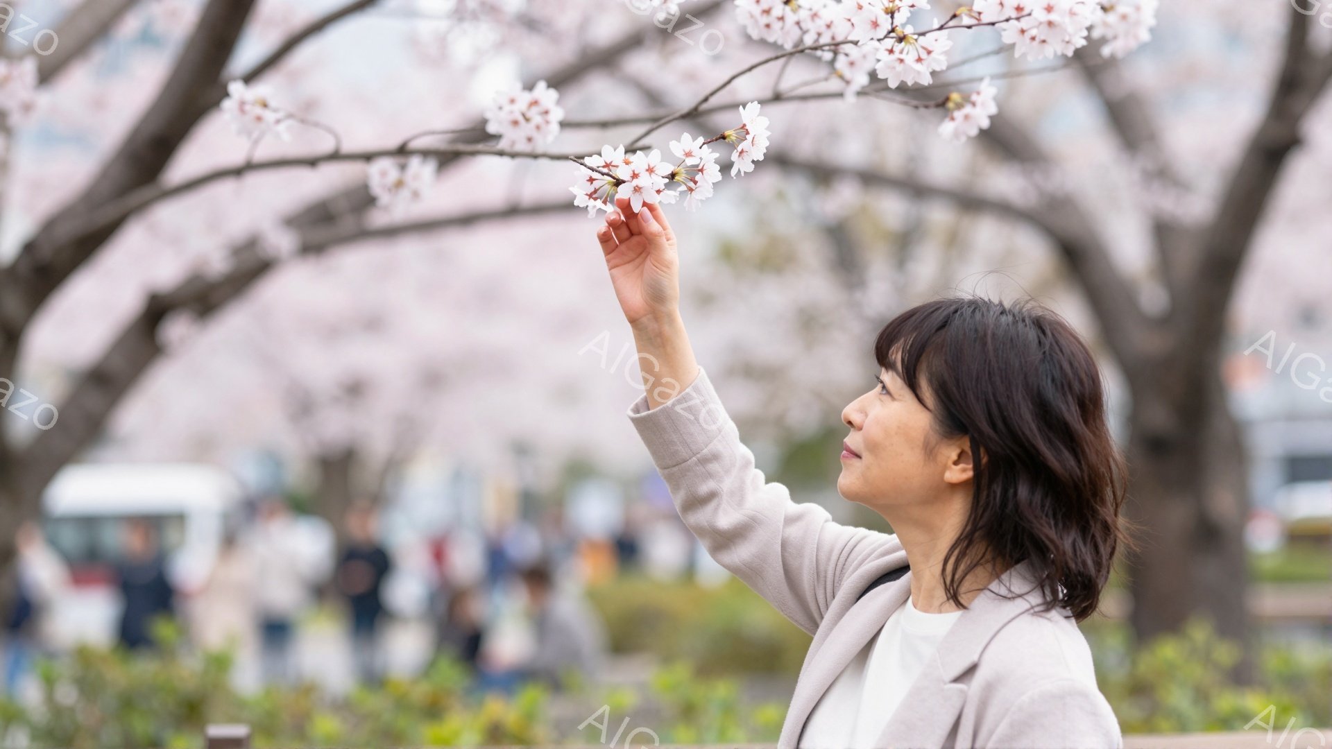 画像には、桜の木の下で上を見上げている女性が写っています。ベージュのジャケットを着ており、短めの黒髪が特徴的で、穏やかな表情を浮かべています。背景にはぼやけた人々と建物、そして桜並木が広がり、春の暖か - AI生成フリー素材