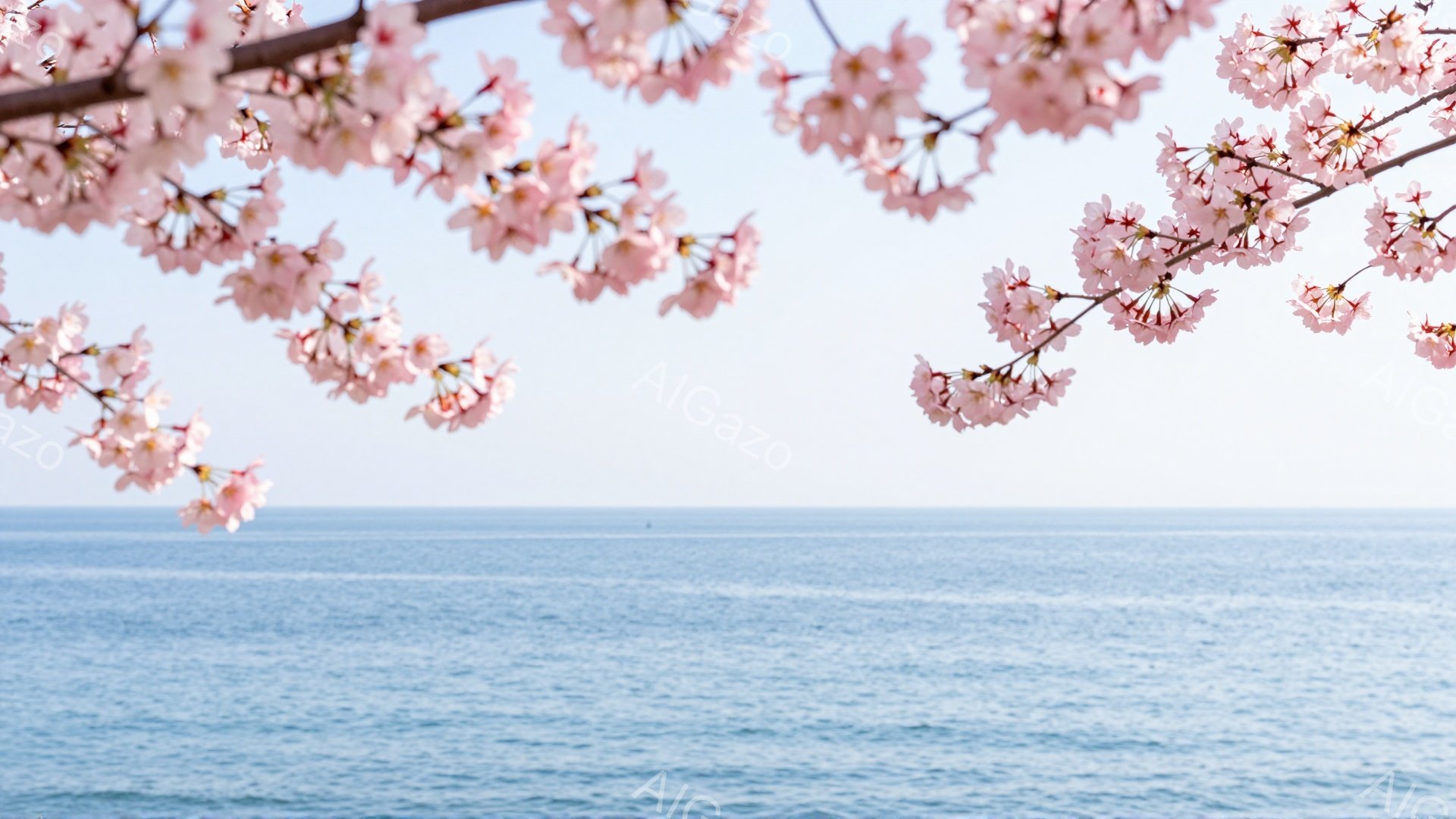 海の上に桜の花が咲き乱れている風景です。淡いピンク色の桜の花びらが、穏やかな青い海と空のグラデーションを縁取り、春の穏やかな雰囲気を醸し出しています。遠くには水平線が見え、静かで平和な情景が広がっています。
