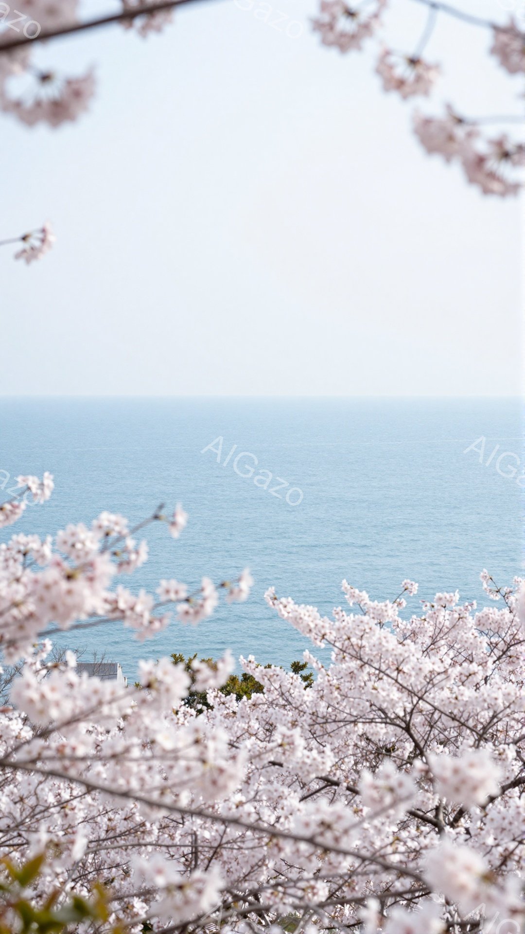 淡いピンク色の桜の花びらが画面全体を覆い、その奥には穏やかな青い海が広がっています。遠くには白い屋根の建物が見え、春の柔らかな日差しが感じられる穏やかな情景です。桜と海が織りなす美しいコントラストが、安らぎと希望に満ちた雰囲気を醸し出しています。
