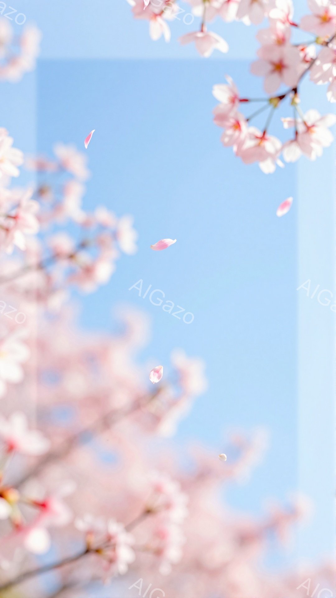 桜の花びらが舞い散る春の風景で、ピンク色の桜の花が画面全体を彩っています。青空を背景に、花びらが軽やかに舞い、春の暖かさと儚さを表現しています。ぼやけた背景には、近代的な建物がわずかに見え隠れし、都会の中の自然の美しさを引き立てています。
