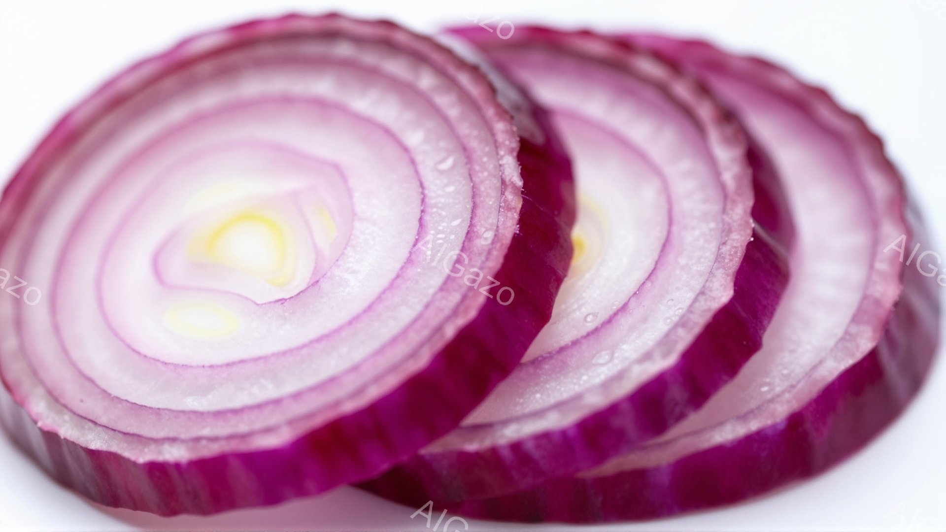 薄紫色のタマネギが薄切りにされ、幾重にも重なった様子が写っている。切り口からは水分が光り、新鮮さを感じさせる。背景は白く、タマネギの鮮やかな色彩が際立っている。