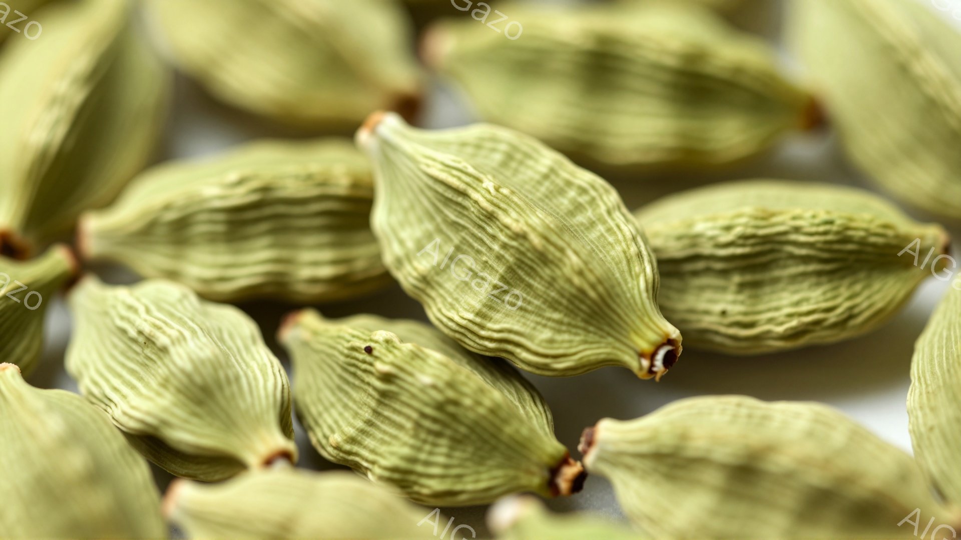 画像は、複数のカルダモンポッドが互いに重なり合って写されています。それらは緑色を帯びた淡い色合いで、表面には細かい筋模様が見られます。背景はぼやけており、ポッドが主な焦点となっています。 - AI生成フリー素材