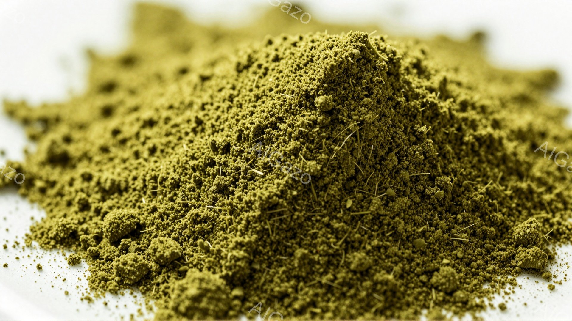 この画像は、白地に細かい緑色の粉末が山積みになっているクローズアップ写真です。粉末は植物由来のようであり、一部に細い繊維状のものが混ざっています。全体的に、自然でオーガニックな印象を与えます。 - AI生成フリー素材