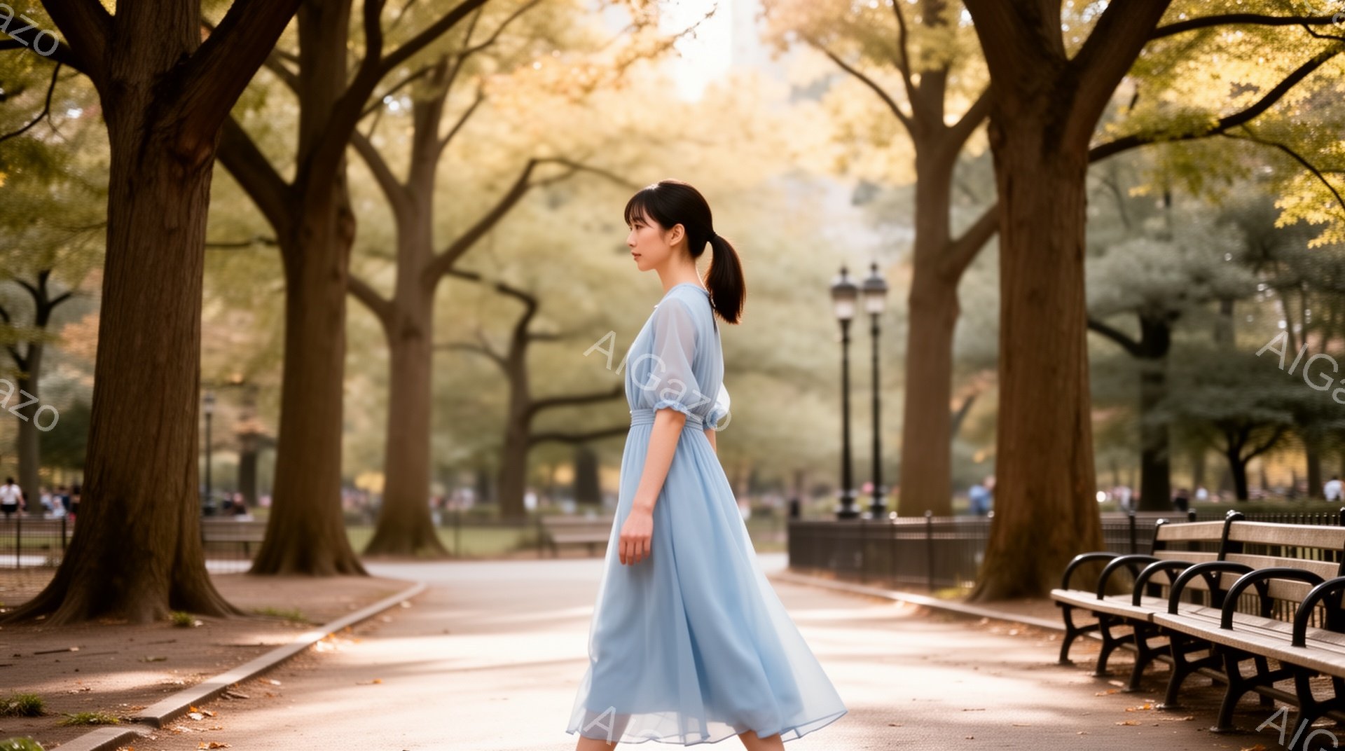 青いパステルカラーのゆったりとしたワンピースを着た女性が、公園の遊歩道を歩いている。彼女は髪を後ろで一つにまとめ、横を向いており、穏やかな表情をしている。背景には高い木々とベンチが並び、遊歩道は明るい日差しに照らされている、穏やかで平和な雰囲気の公園の風景である。
