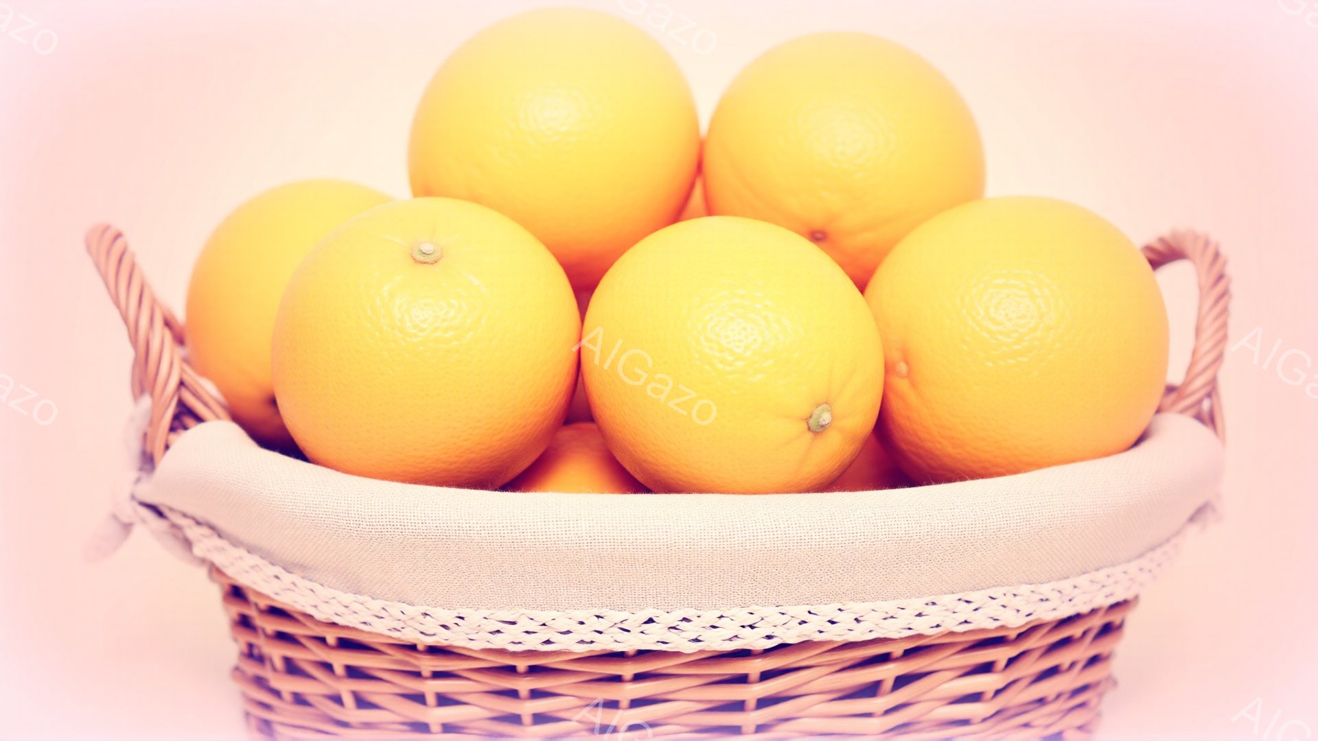 鮮やかなオレンジが、白い布ライニングが施された、編み込みのバスケットにぎっしりと詰まっています。バスケットは少し傾いており、オレンジが溢れ出しそうな印象を与えます。背景は淡いピンク色で、全体的に暖かく、明るい雰囲気を醸し出しています。