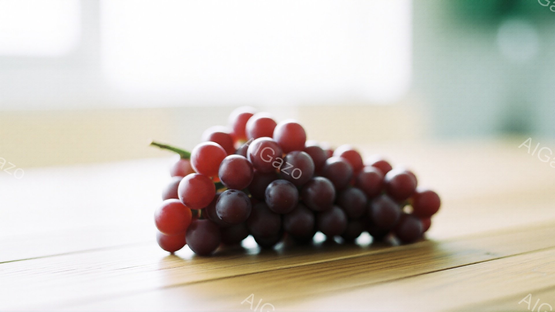 濃い紫色のぶどうの房が、木製のテーブルの上に置かれている。光沢のある粒が密集し、自然な影がテーブル上に落ちている。背景はぼやけており、明るい室内であるように見える。 - AI生成フリー素材