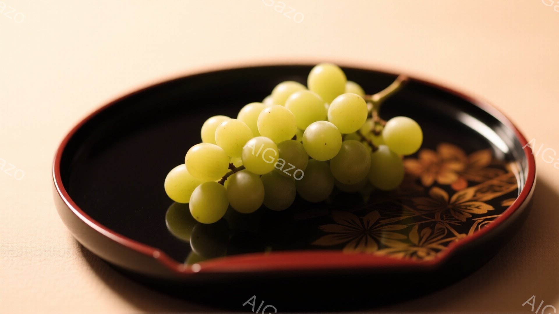 漆塗りの黒い皿に、一房の緑色のぶどうが乗っています。皿の縁は赤く、背景には抽象的な金色の模様が施されています。全体的に落ち着いた色調で、上品で洗練された雰囲気を醸し出しています。