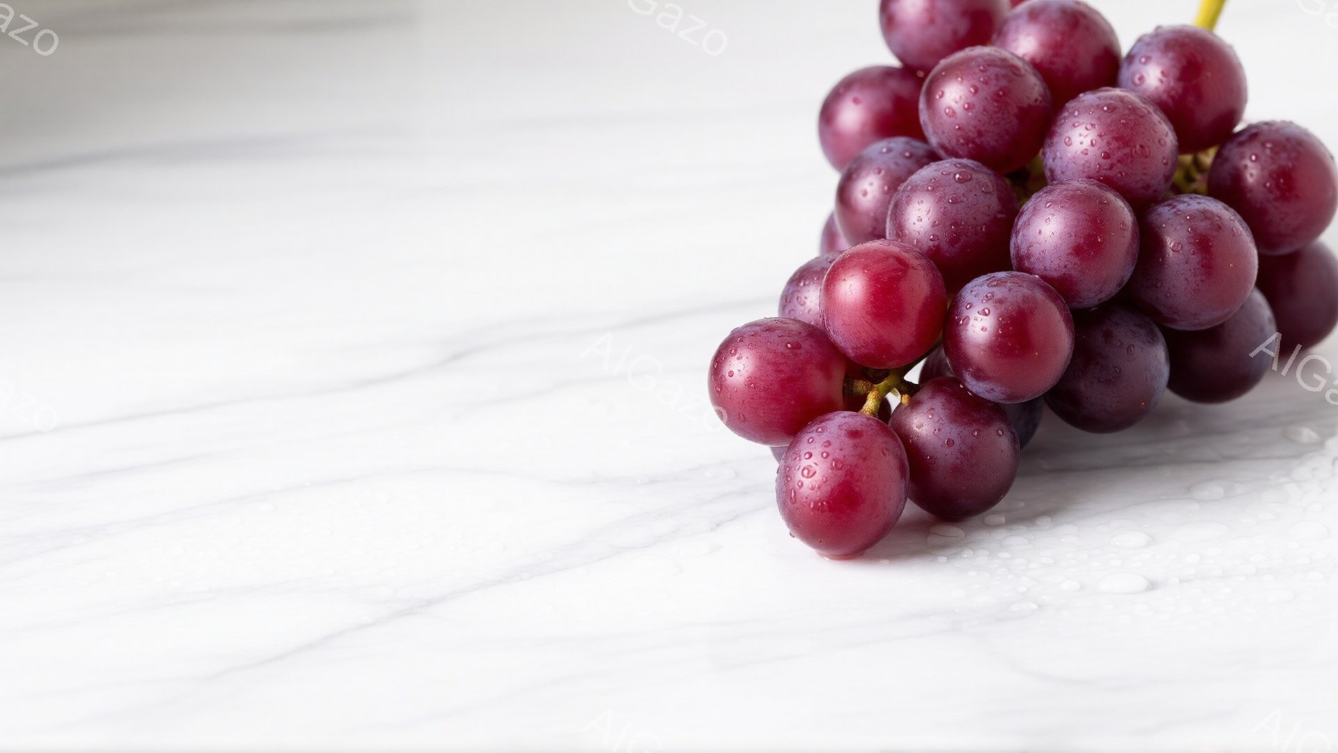 鮮やかな赤紫色のぶどうの房が、白い大理石のような背景の上に置かれています。ぶどうの表面には水滴がついており、新鮮でみずみずしい印象を与えます。背景は滑らかで、ぶどうの色と質感を引き立てています。