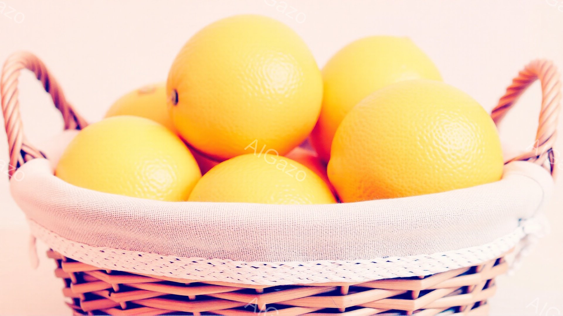 籐編みのバスケットに鮮やかなオレンジがたっぷり詰まっています。内側には白い布が敷かれており、オレンジの鮮やかさを引き立てています。全体的に明るく、みずみずしい果物の魅力が伝わってくる雰囲気です。