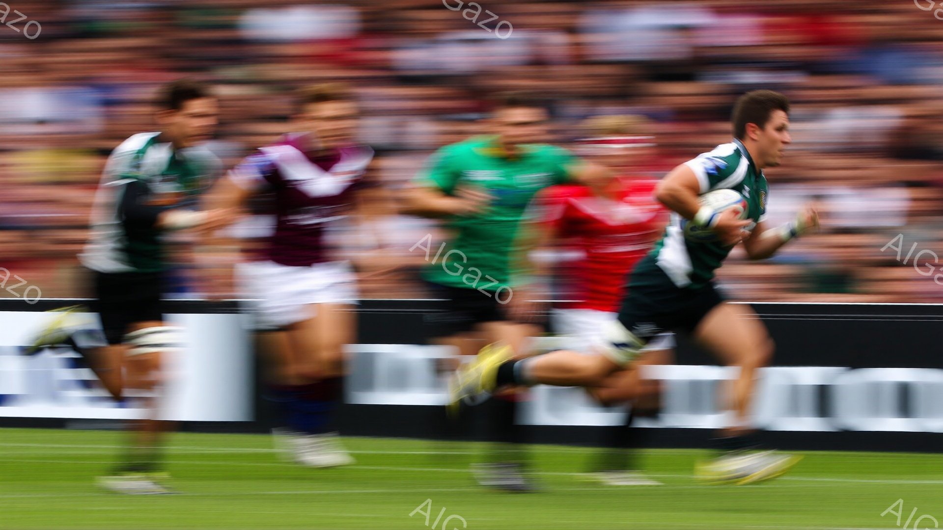 ラグビーの試合中の様子で、複数の選手がピッチを疾走している。緑、紺、赤色のユニフォームを着用した選手たちは、モーションブラーがかかり、動きの速さが強調されている。背景には観客席が見え、鮮やかな緑の芝生 - AI生成フリー素材
