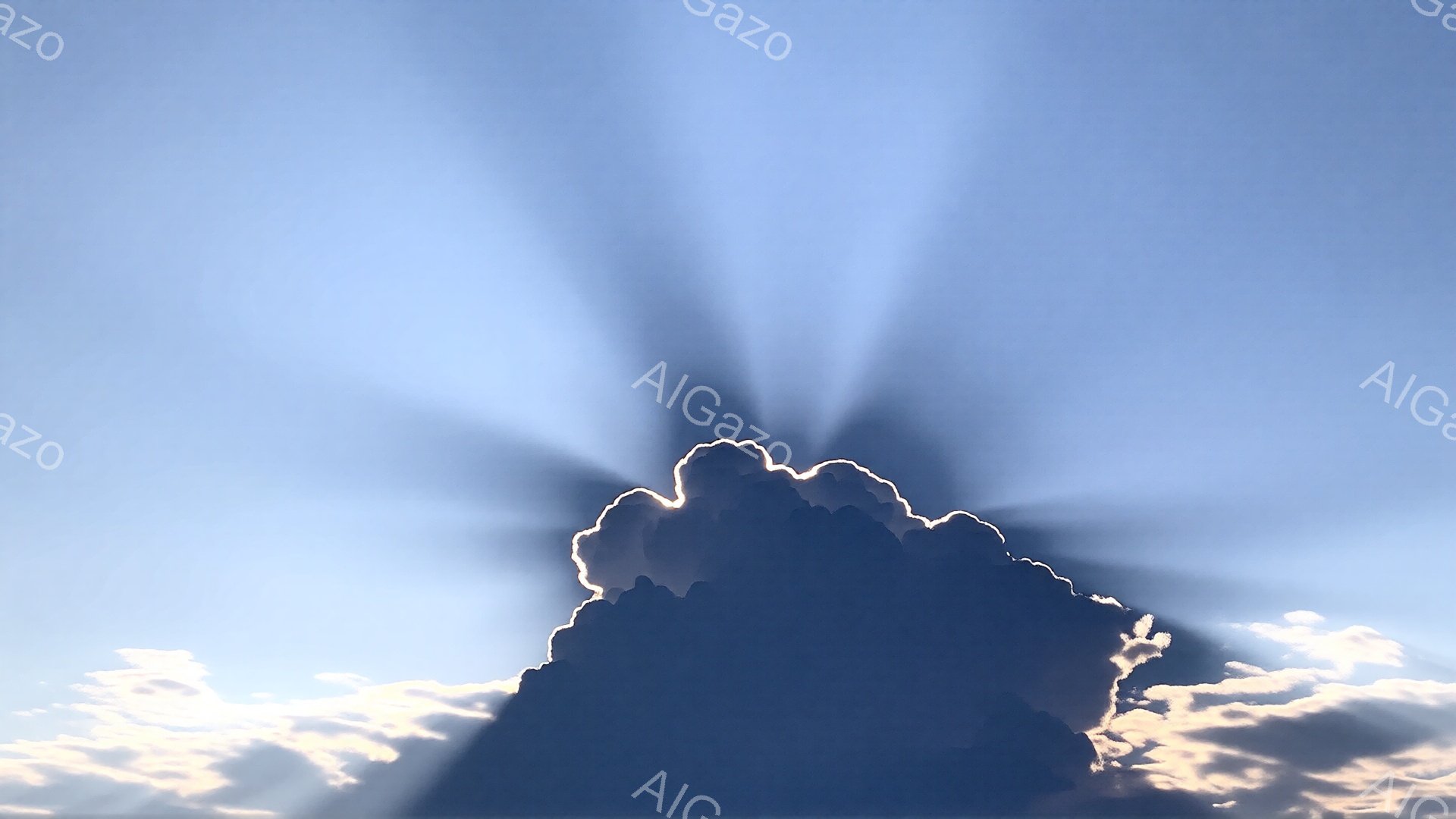 空には、暗い影を持つ大きな雲が浮かび、そこから強い光線が放射状に広がっている。雲の下には、わずかに薄い雲が広がり、全体的に穏やかで神秘的な雰囲気を醸し出している。鮮やかな青空とのコントラストが、荘厳な自然の力を感じさせる。