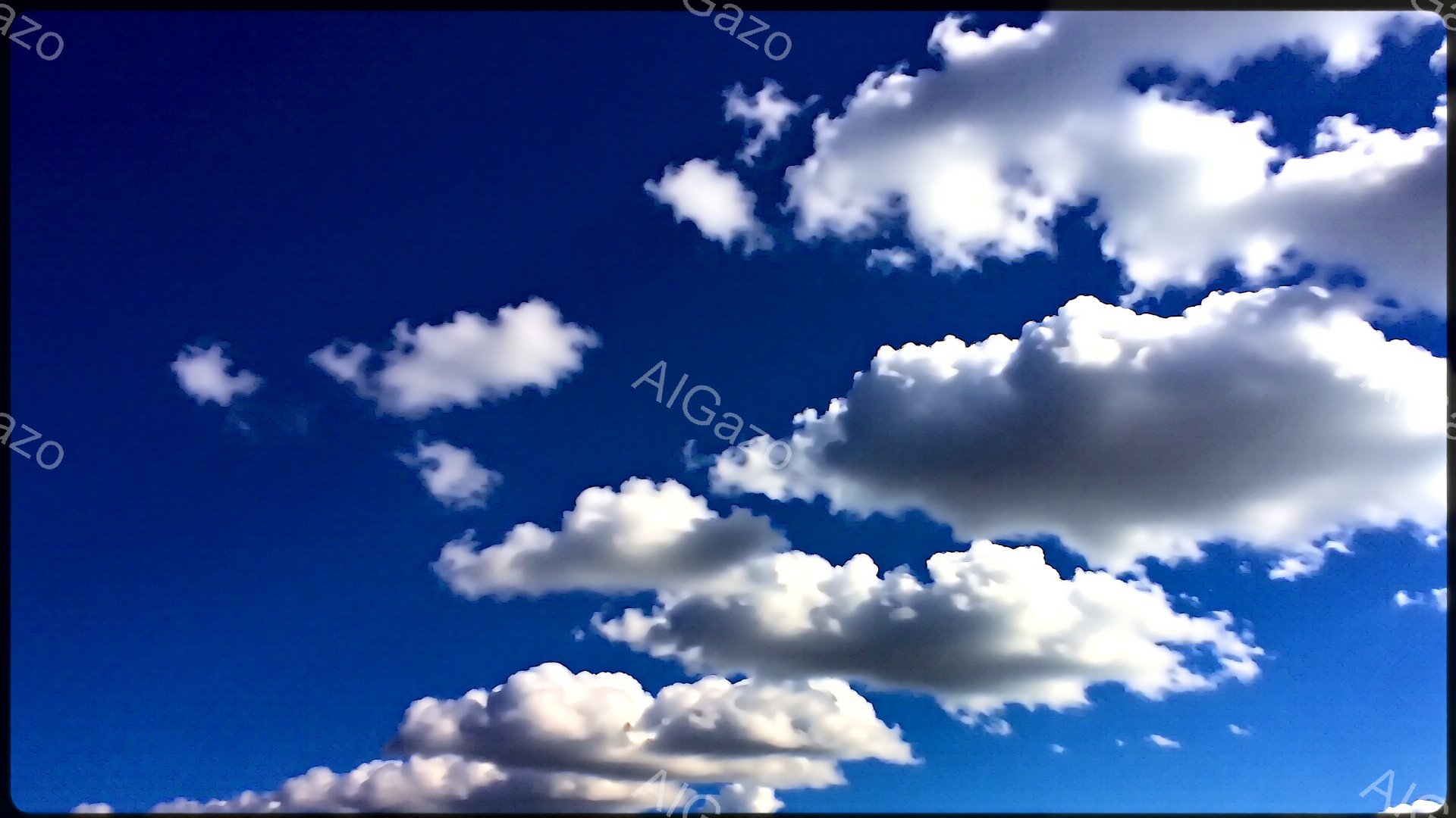 鮮やかな青空に、白いふわふわとした雲が浮かんでいます。雲は様々な形をしており、まるで綿菓子のように柔らかい印象を与えます。快晴で、爽やかな夏の日のような雰囲気が伝わってきます。