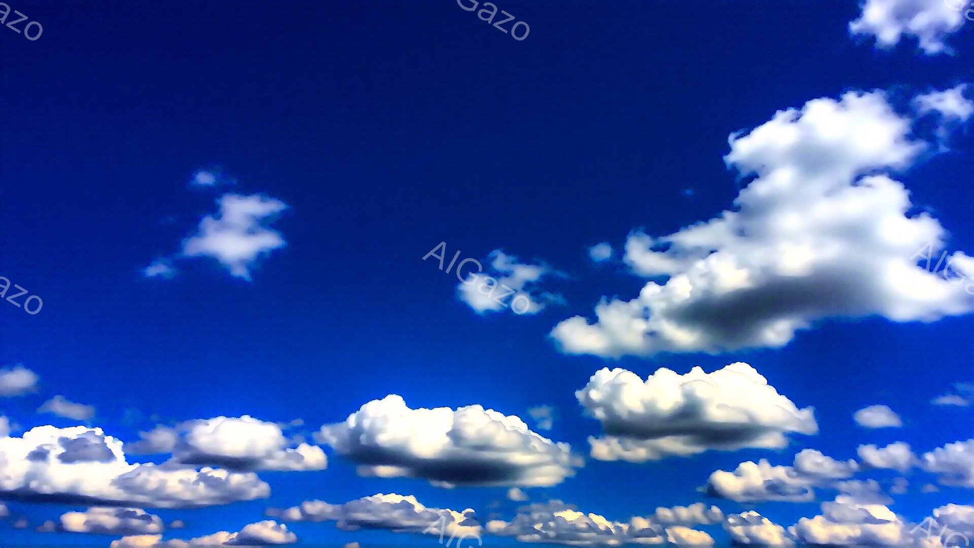 鮮やかな青空に、白い雲がふわふわと浮かんでいます。雲は様々な形をしており、まるで綿菓子のように見えます。晴れた日の穏やかな空模様が印象的です。