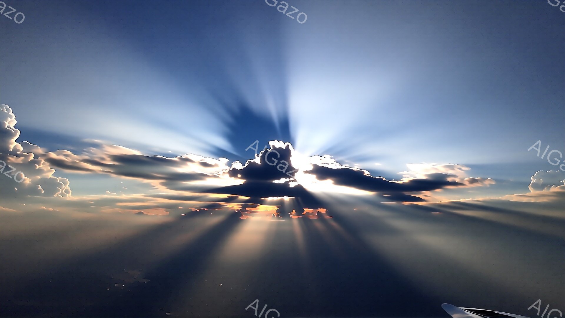雲海から差し込む太陽光線が印象的な空の風景です。暗い影と明るい光が対照的に描かれ、力強い光芒が空を染め上げています。翼の一部がわずかに見え、飛行機内から撮影されたものであることがわかります。