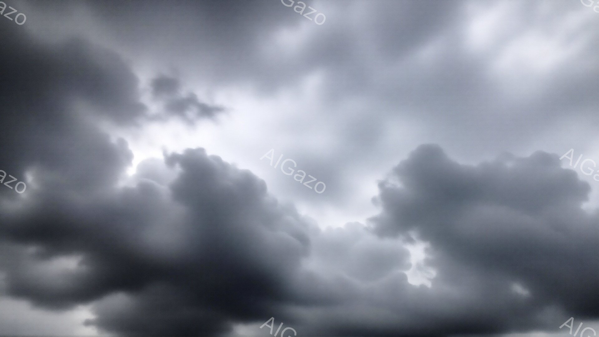 濃い灰色の雲が空を覆い、強いコントラストで明るい隙間から光が差し込んでいる。雲の形は不規則で、まるで巨大な山脈のように重なり合っている。この空模様は、嵐の前、あるいは嵐の最中を連想させる、ドラマチックで緊張感のある雰囲気を醸し出している。