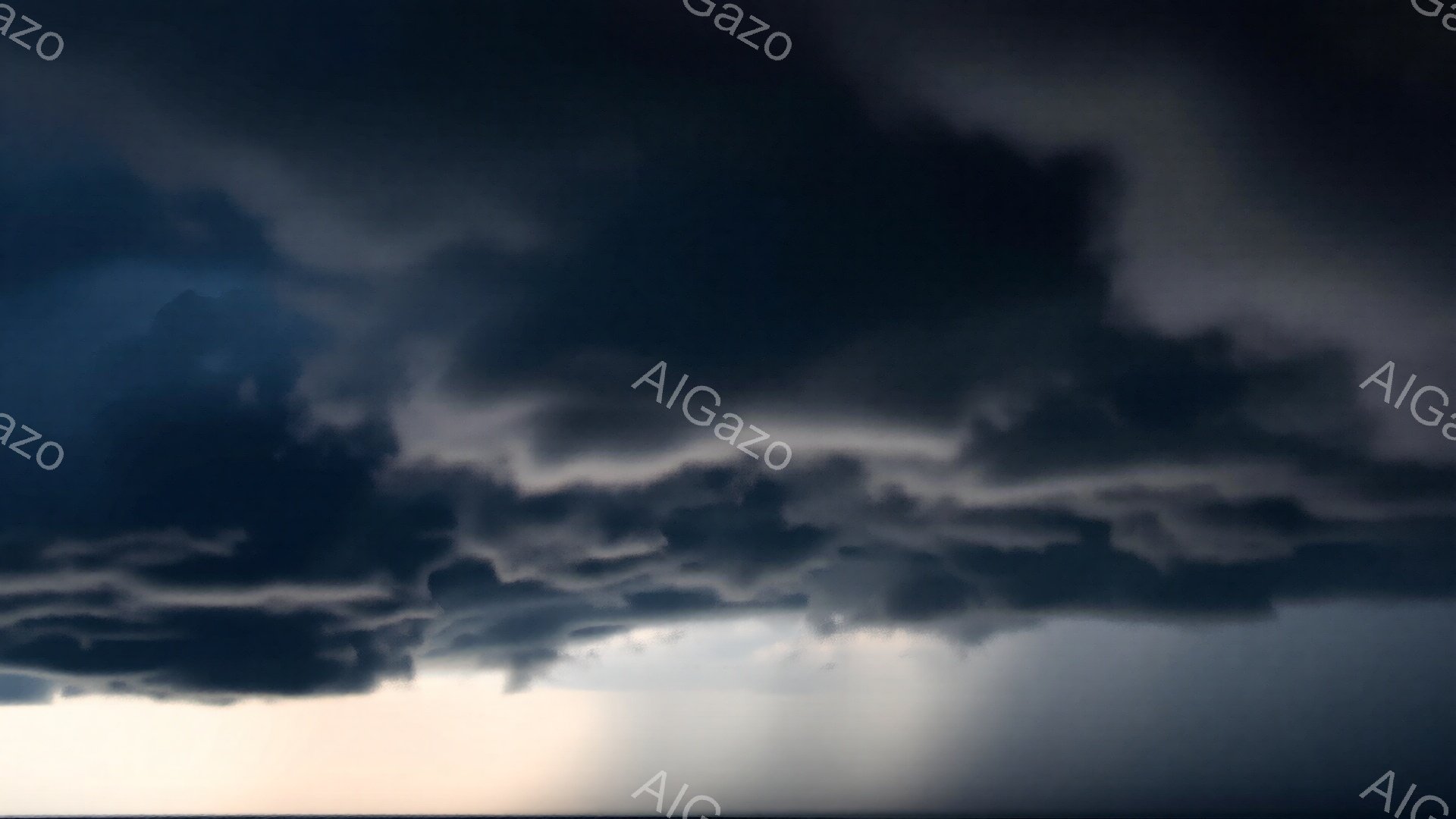 厚い暗雲が空を覆い、下には薄明かりが差し込んでいる。雲の形は重く、不穏な気配を感じさせるが、光が雲間から差し込むことで、わずかな希望の兆しが見える。全体的に、嵐の前後のドラマチックな空模様が印象的である。