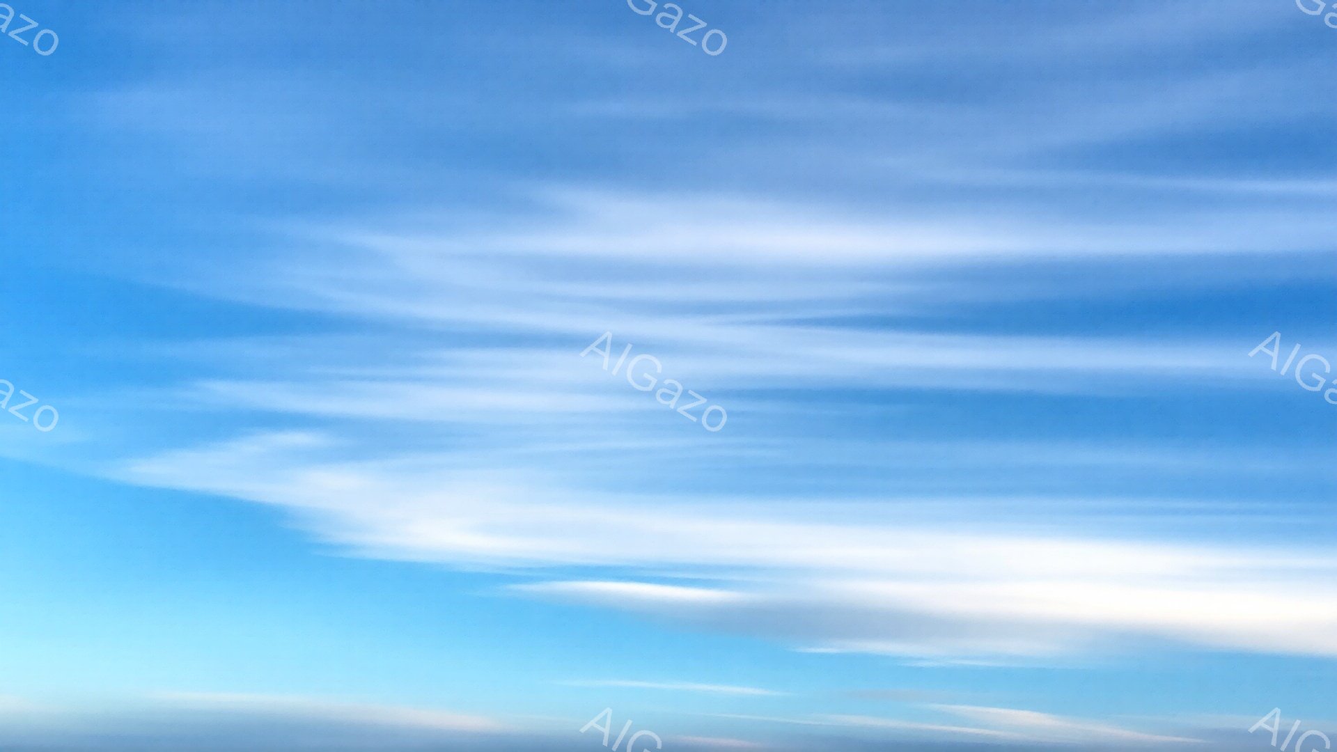 空は鮮やかな青色で、白い筋状の雲が流れています。雲はまるで筆で描かれた絵のようで、空全体に穏やかな雰囲気を醸し出しています。爽やかで晴れた日の空模様です。