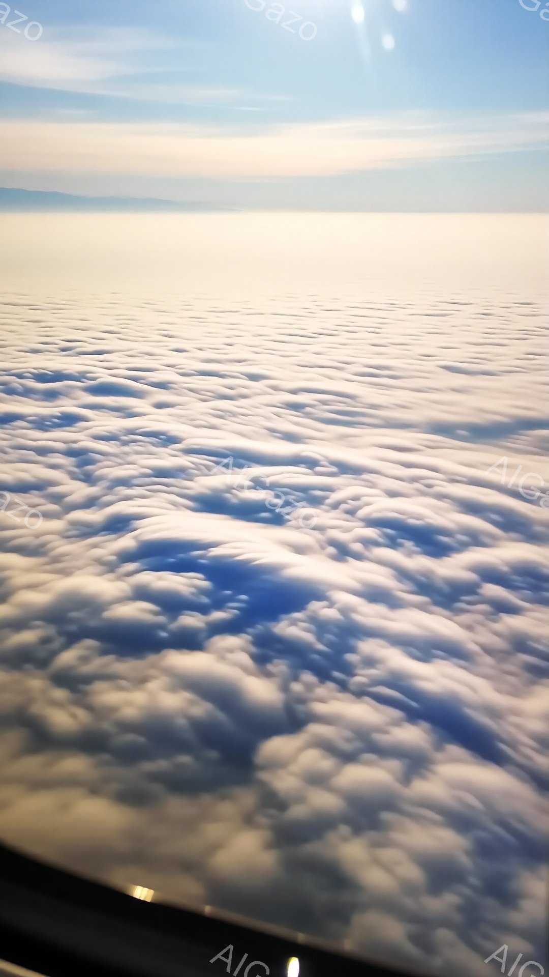 雲海が広がり、まるで白い波がどこまでも続いているかのような壮大な光景です。太陽の光が雲を照らし、明るい光と影が織りなすコントラストが印象的です。空は澄み切った青色で、高い視点から見下ろす景色は、静けさ - AI生成フリー素材