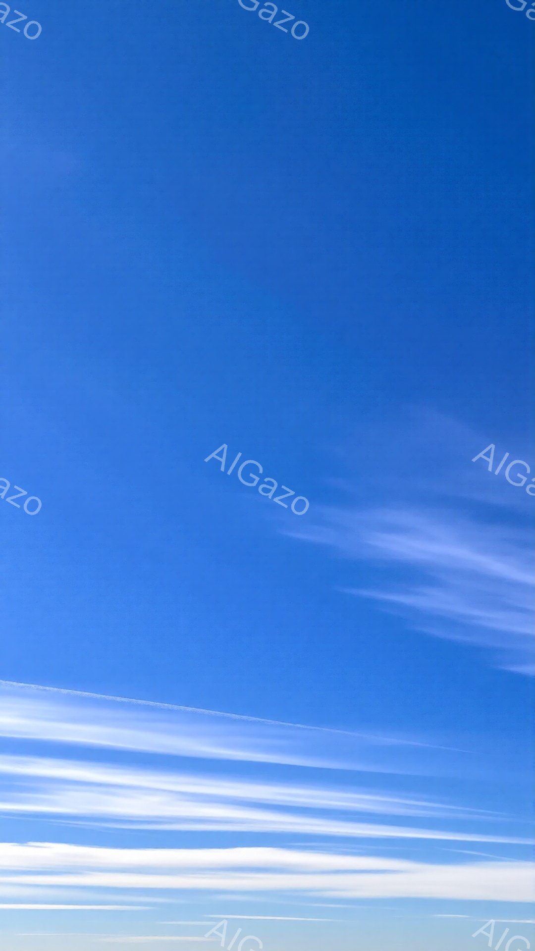 鮮やかな青空に白い筋状の雲が広がっている様子が写っています。雲は薄く、空全体に繊細な模様を描き出しており、飛行機の航跡のように見えます。穏やかで爽やかな、晴天の日の空の雰囲気が伝わってきます。
